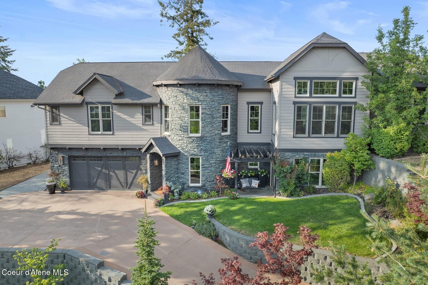 Two-story home with a stone turret, double garage, and landscaped front yard.