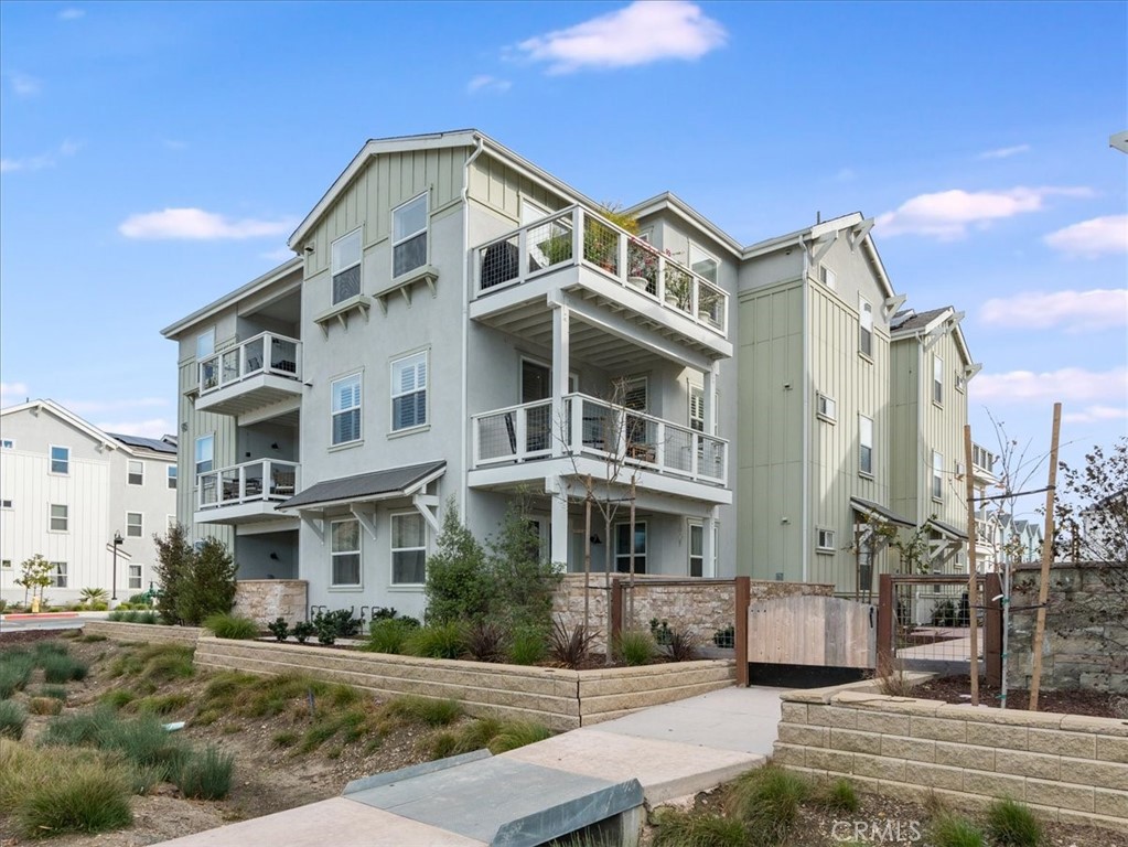 Multi-story residential building with stacked balconies and a gated landscaped entrance.