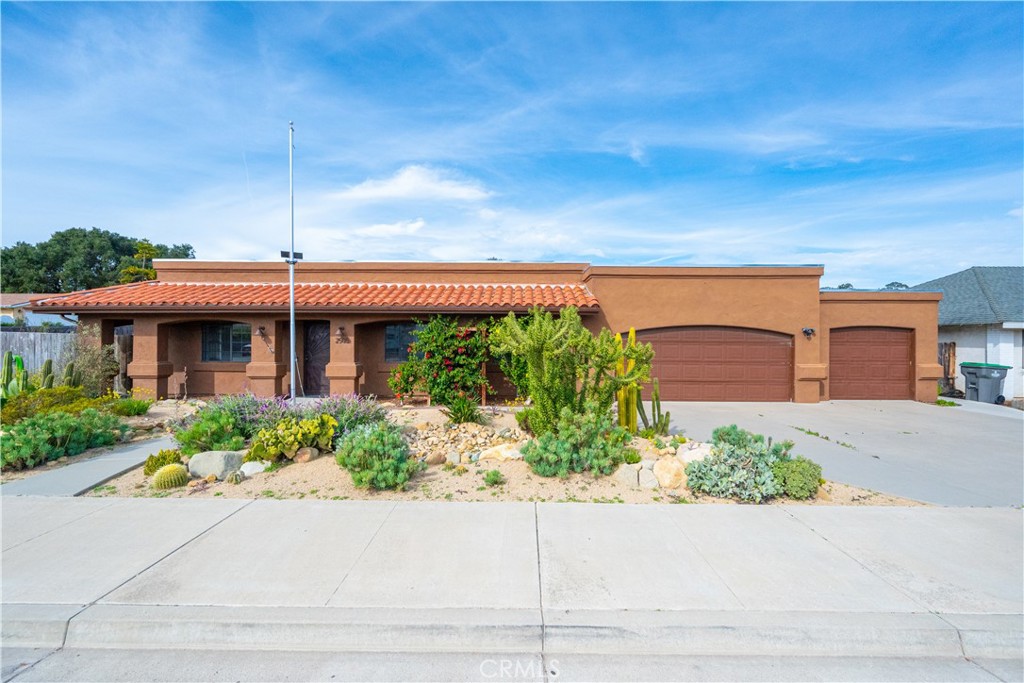 Single-story brown stucco home with a tile roof, two-car garage, and drought-tolerant landscaping.
