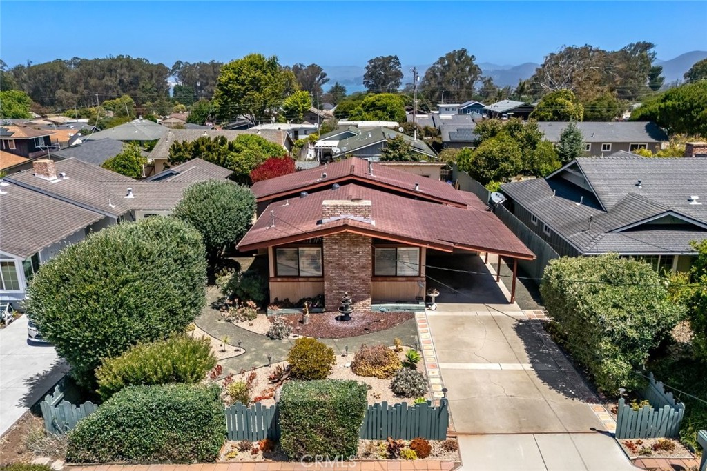 Aerial view of a brick home with a red roof, landscaped yard, and long driveway.