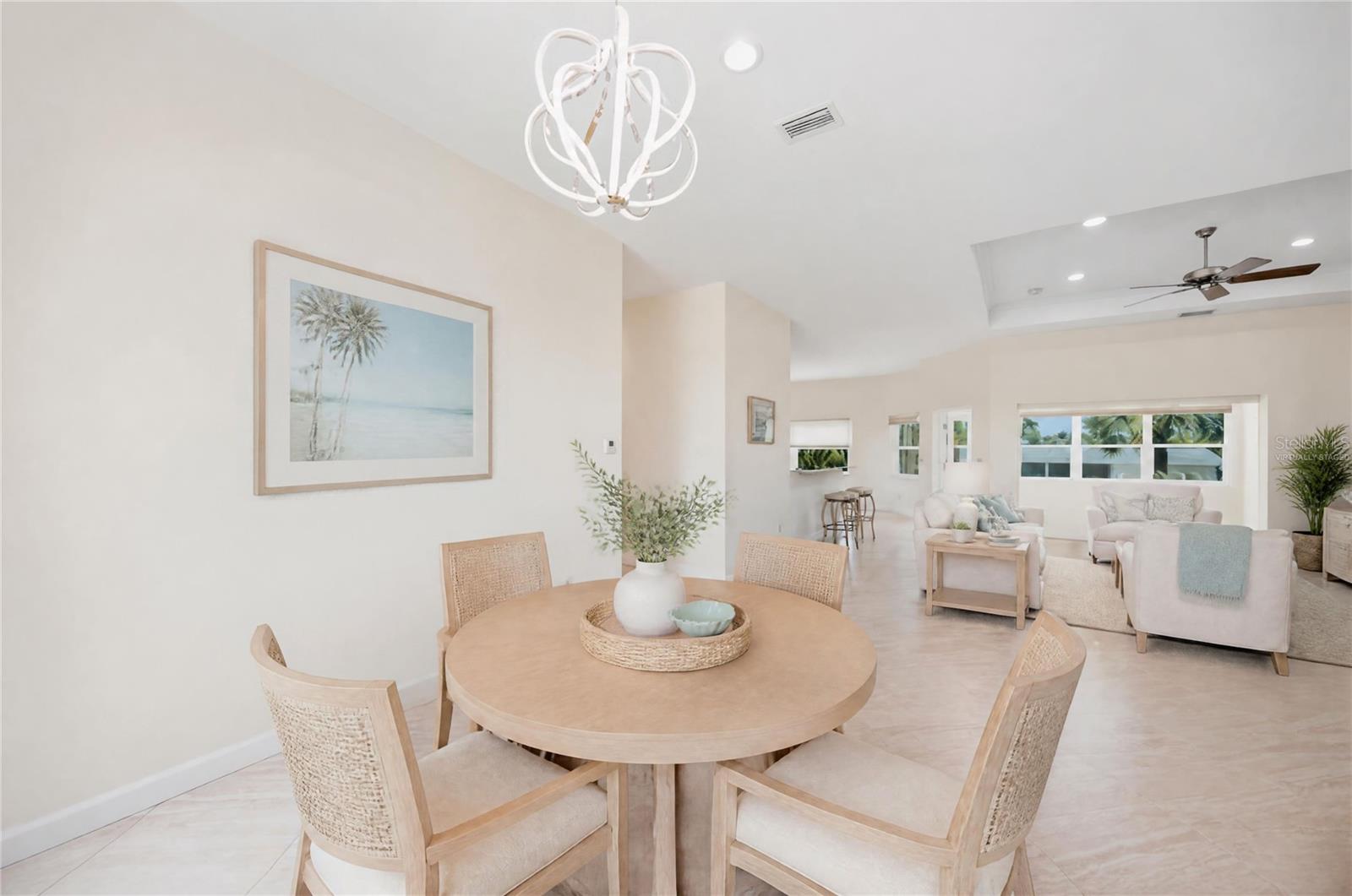 Dining area with a round wood table and woven chairs opening into a bright living room.
