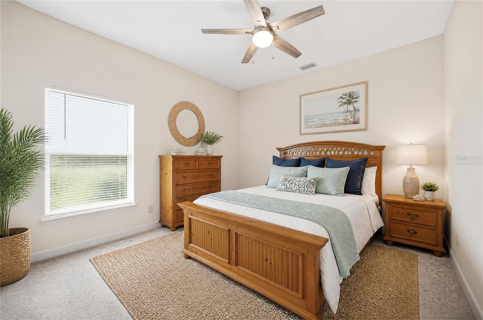 Bedroom with a wooden bed, pale blue bedding, matching dressers, and a ceiling fan.