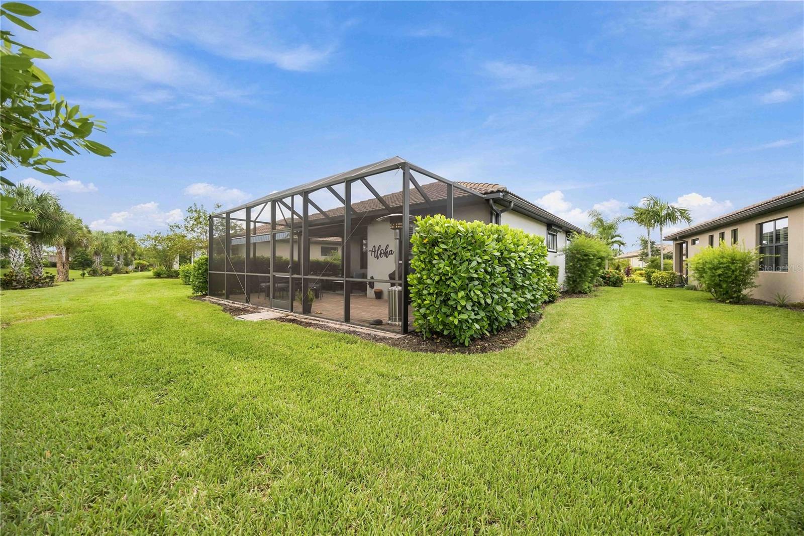 Home with a large screened lanai, patio chairs, and a broad lawn.