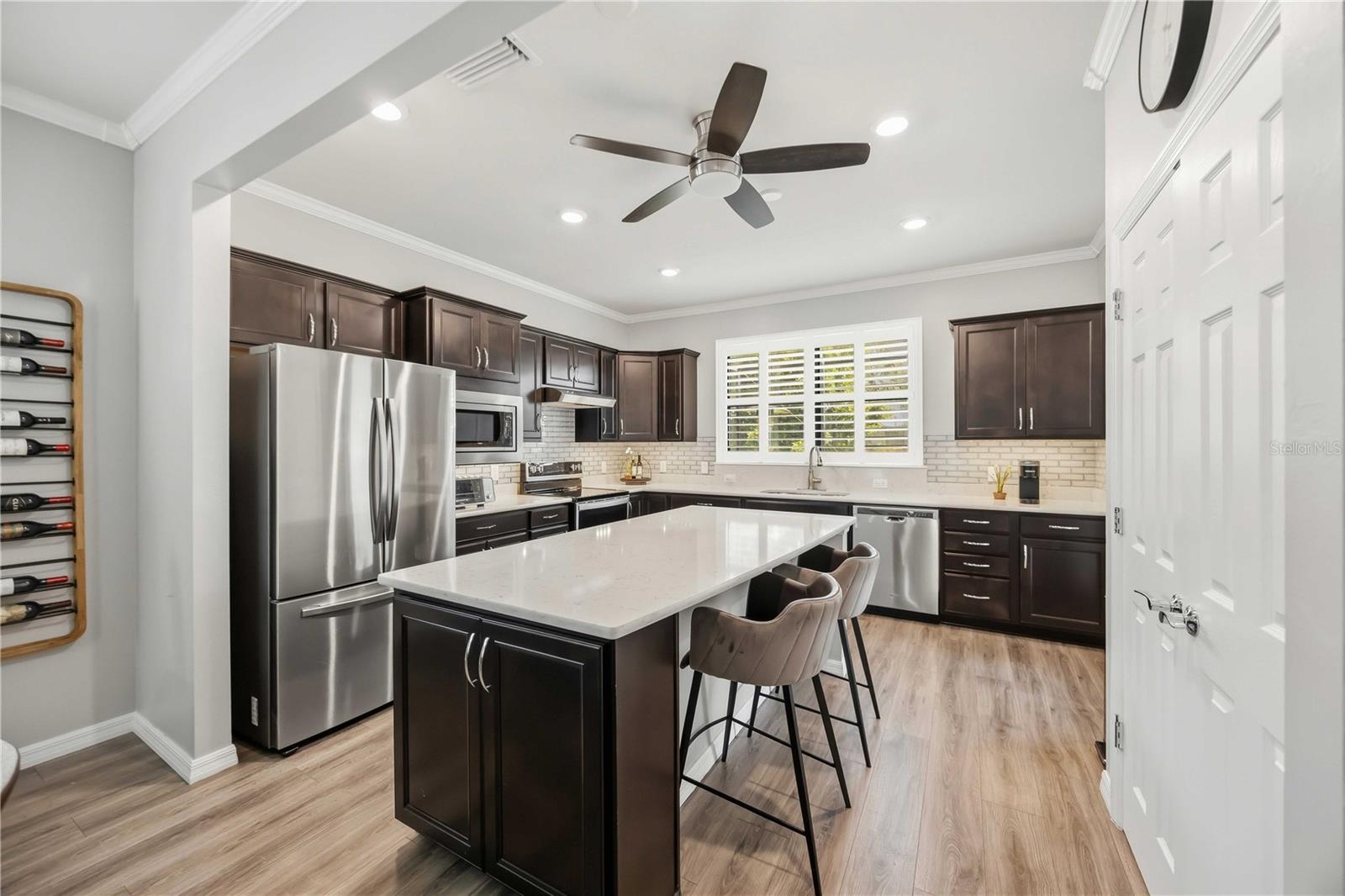 Kitchen with dark cabinets, stainless appliances, and a large white island with bar seating.