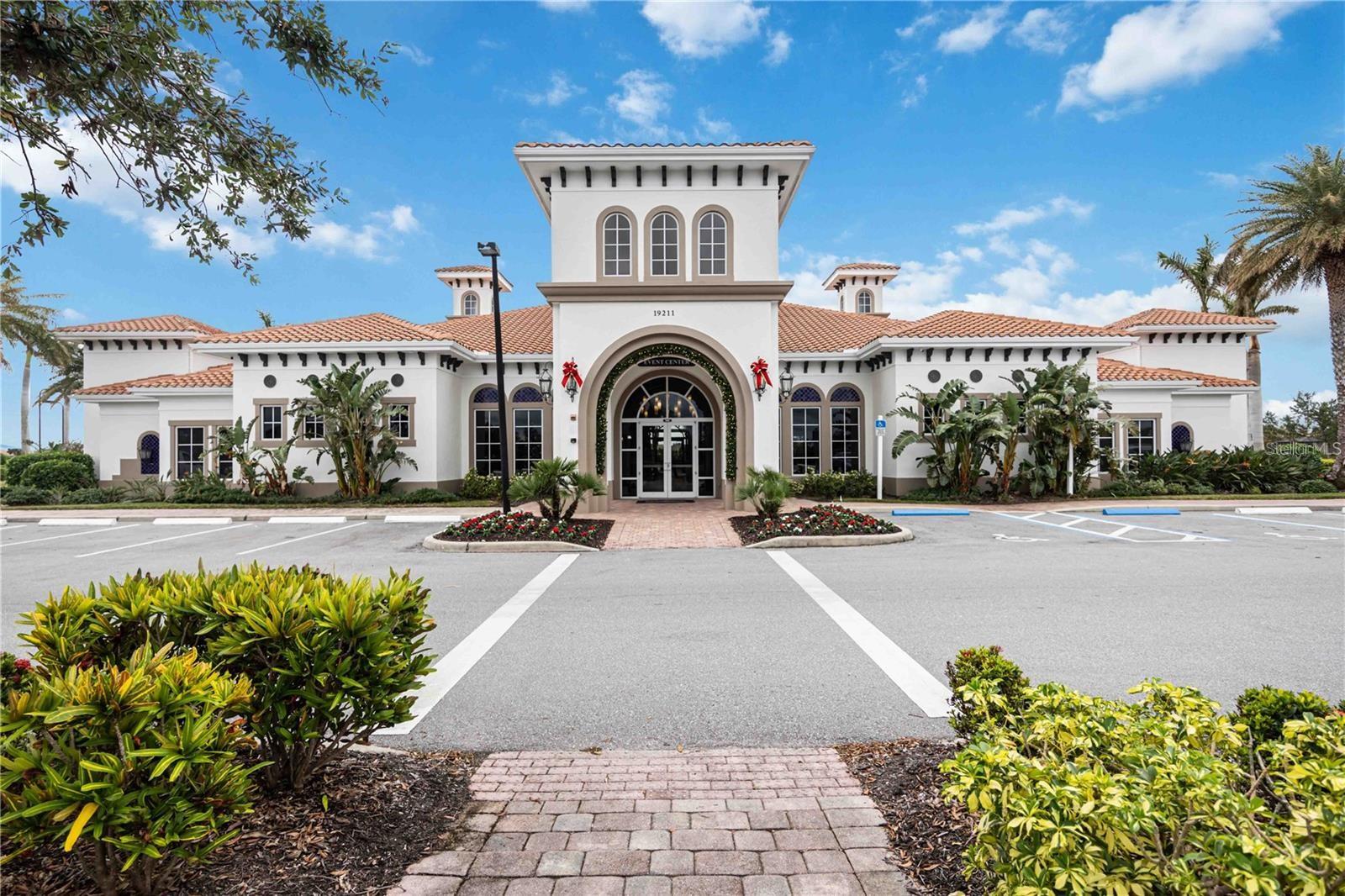 Community event center with a tall arched entrance, terracotta tile roof, and landscaped grounds.