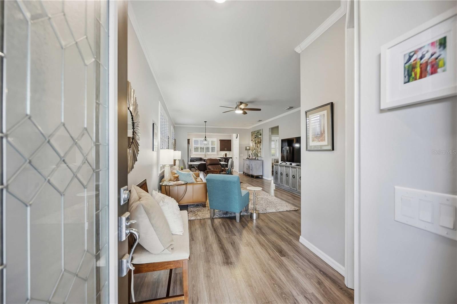 Furnished open-plan living room with wood-look floors, a blue accent chair, and the kitchen beyond.