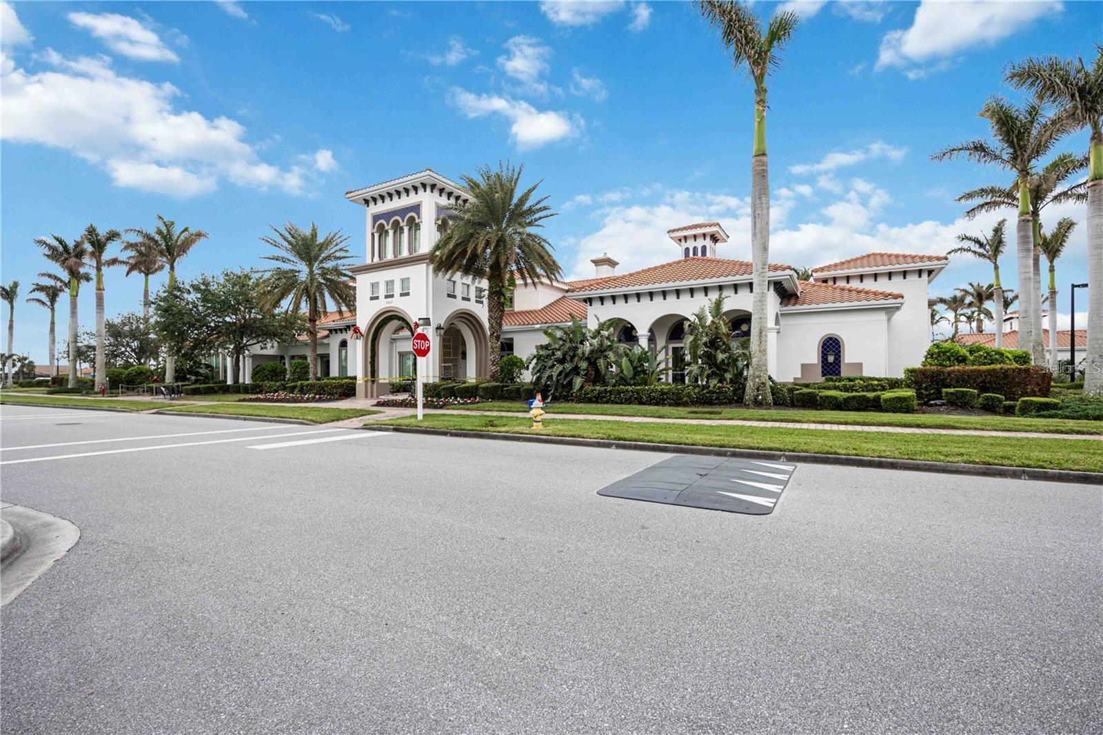 Mediterranean-style community building with arched entrances, terracotta roofs, and palm trees.