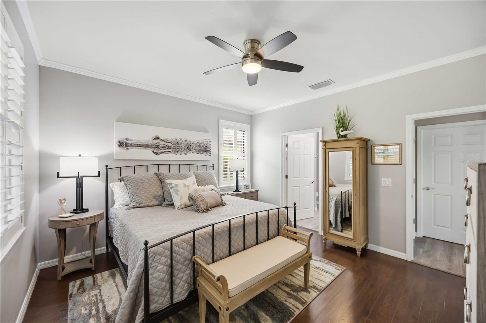 Staged bedroom with a gray quilted bed, black metal frame, and wood bench.
