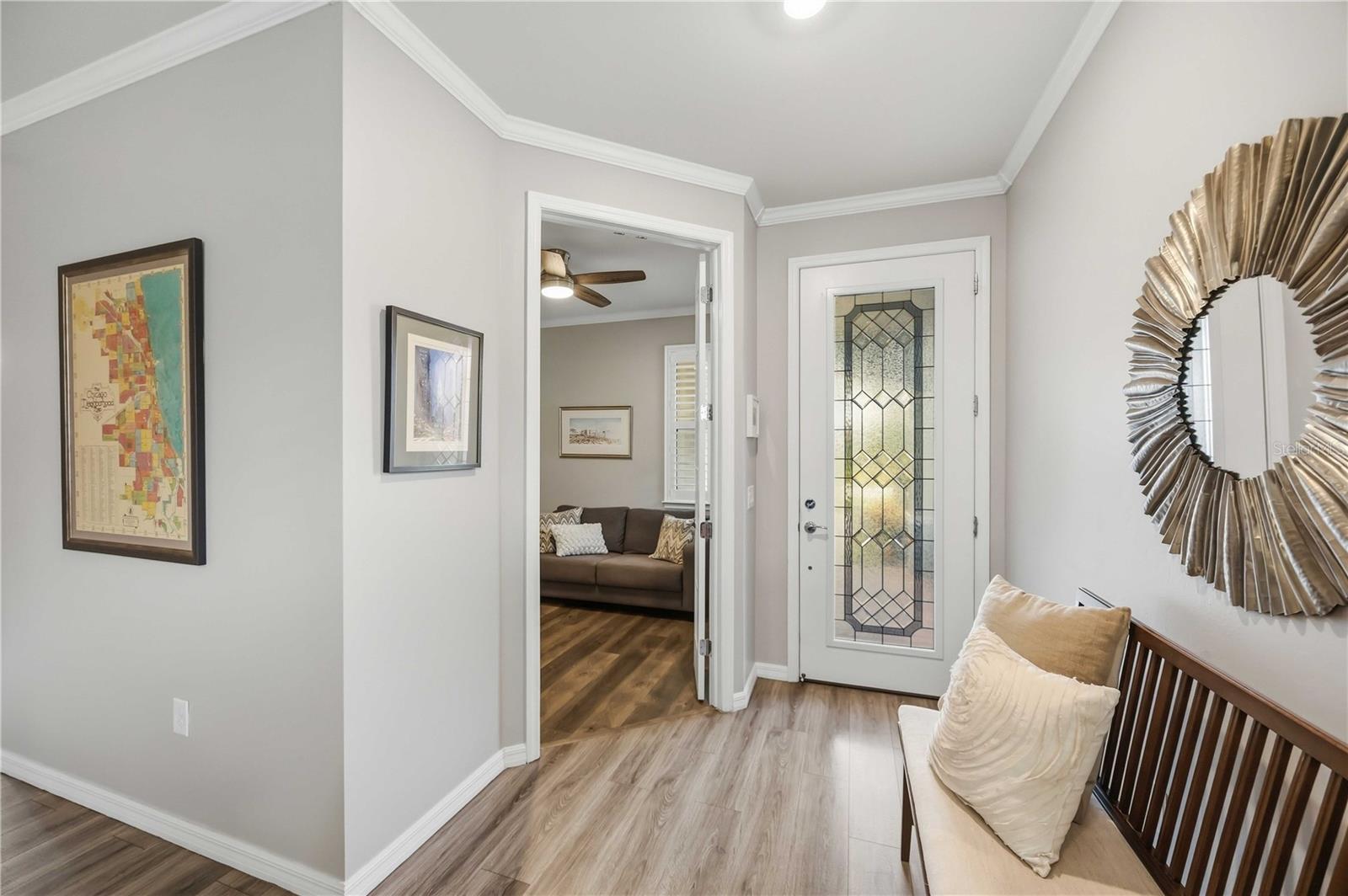 Furnished entryway with a decorative glass front door, cushioned bench, and view into the living room.