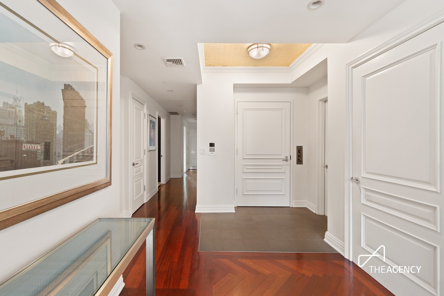 Apartment entry foyer with tiled flooring, rich hardwood floors, and a framed cityscape print.