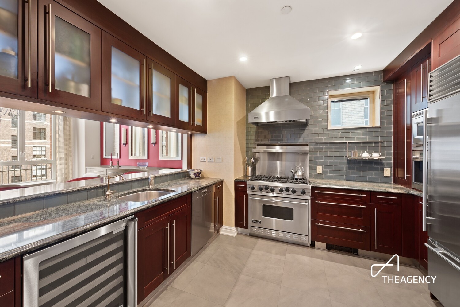 Kitchen with dark wood cabinetry, granite counters, stainless appliances, and a large gas range.