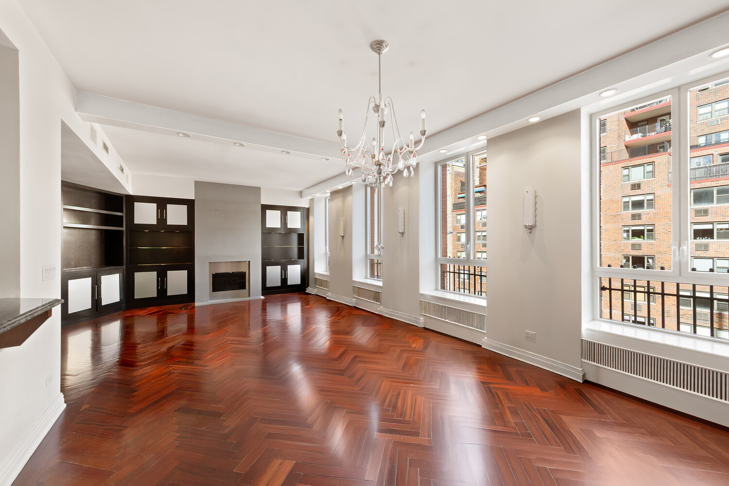 Unfurnished living room with herringbone floors, built-in shelving, a fireplace, and large windows.