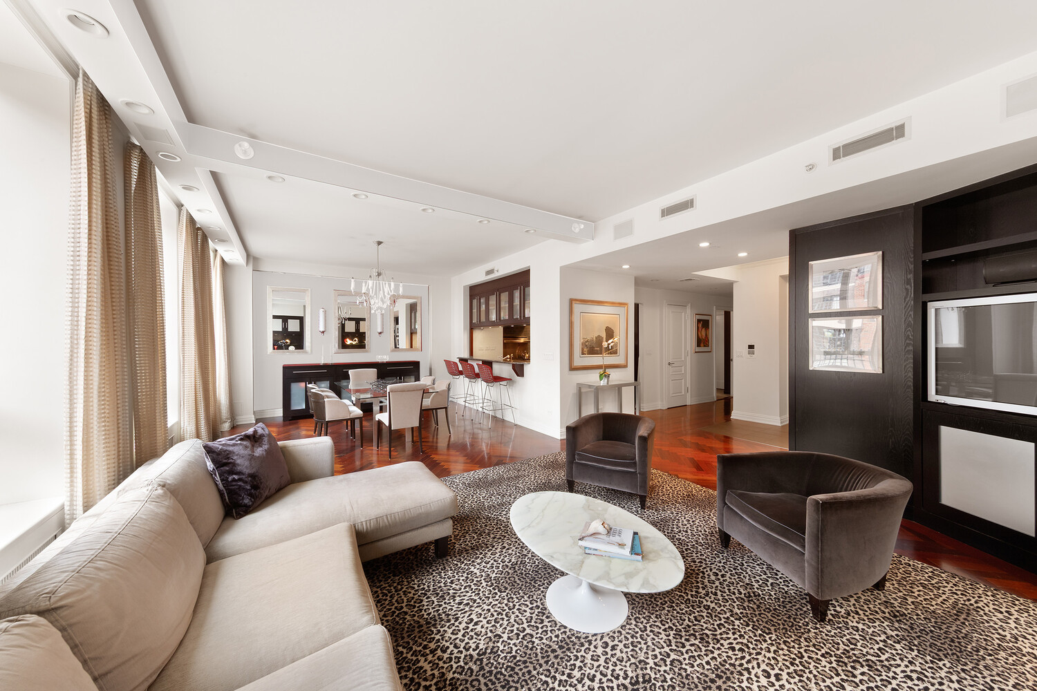 Open-plan living room with beige sectional, leopard-print rug, and dining area beyond.