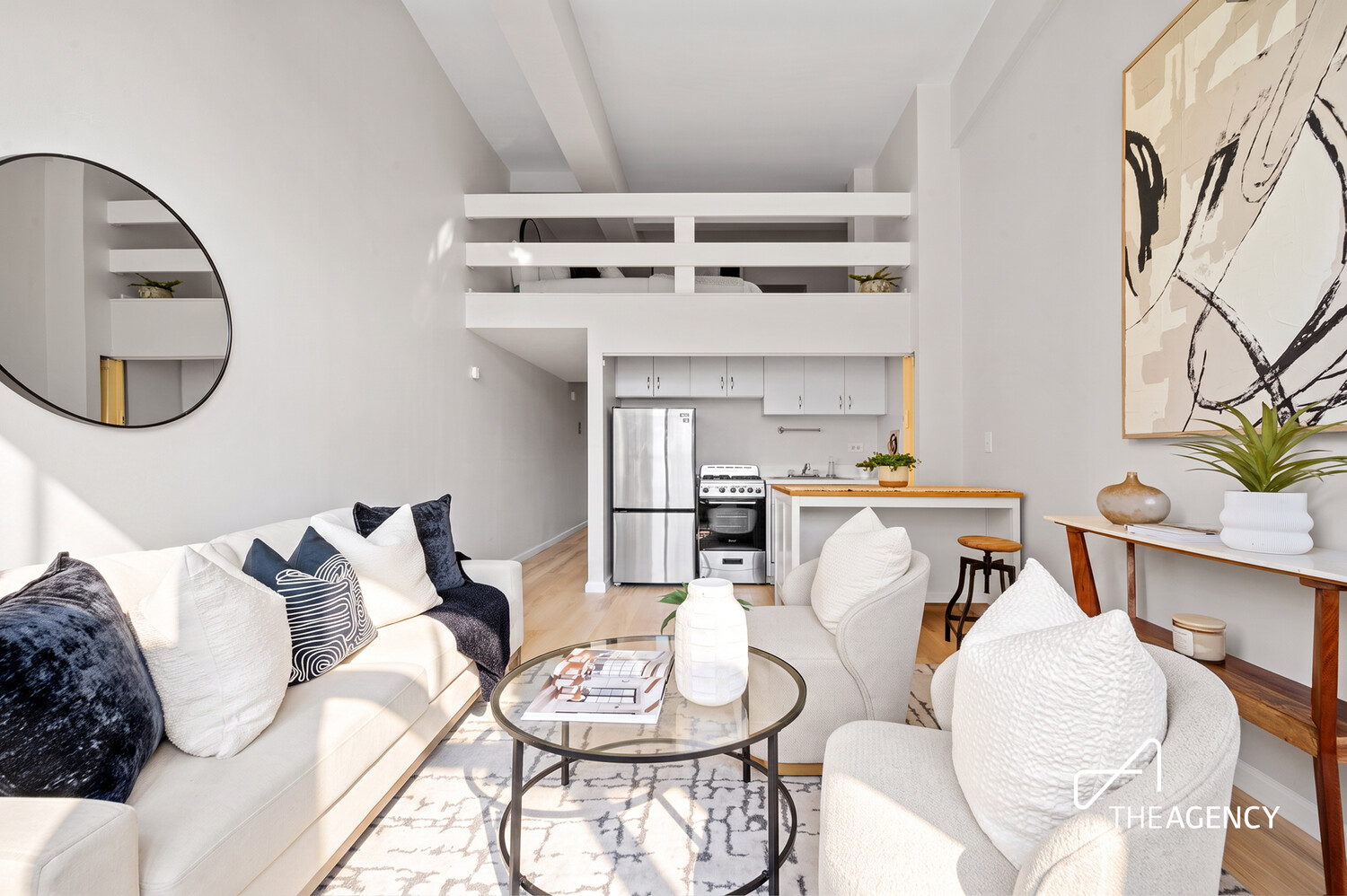 Furnished apartment living room with a high ceiling, white seating, and an open kitchen.