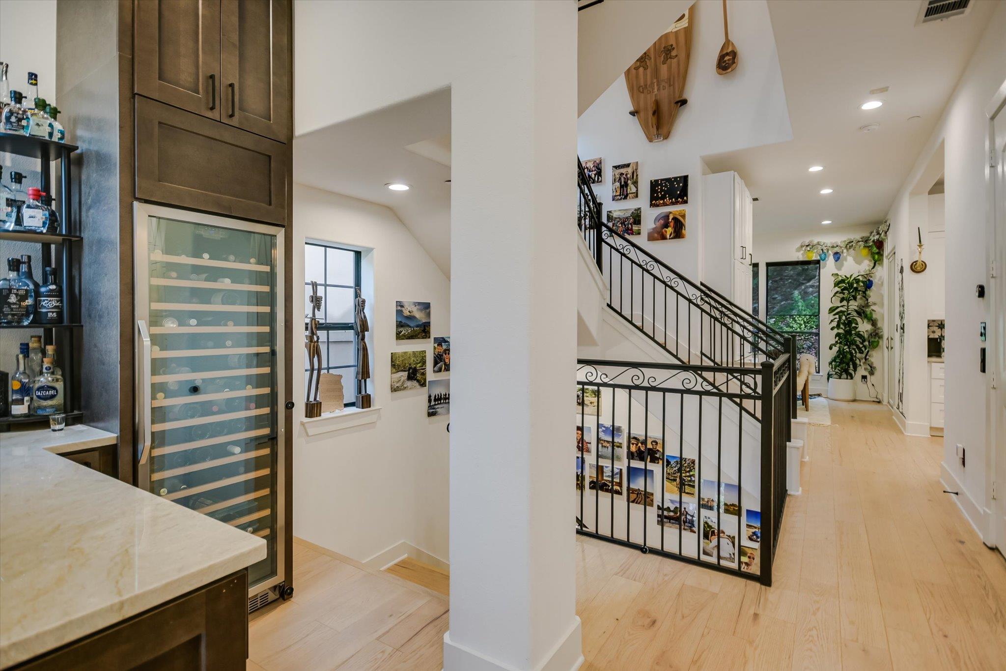 Entry hall with a black iron staircase railing and built-in glass-front wine refrigerator.