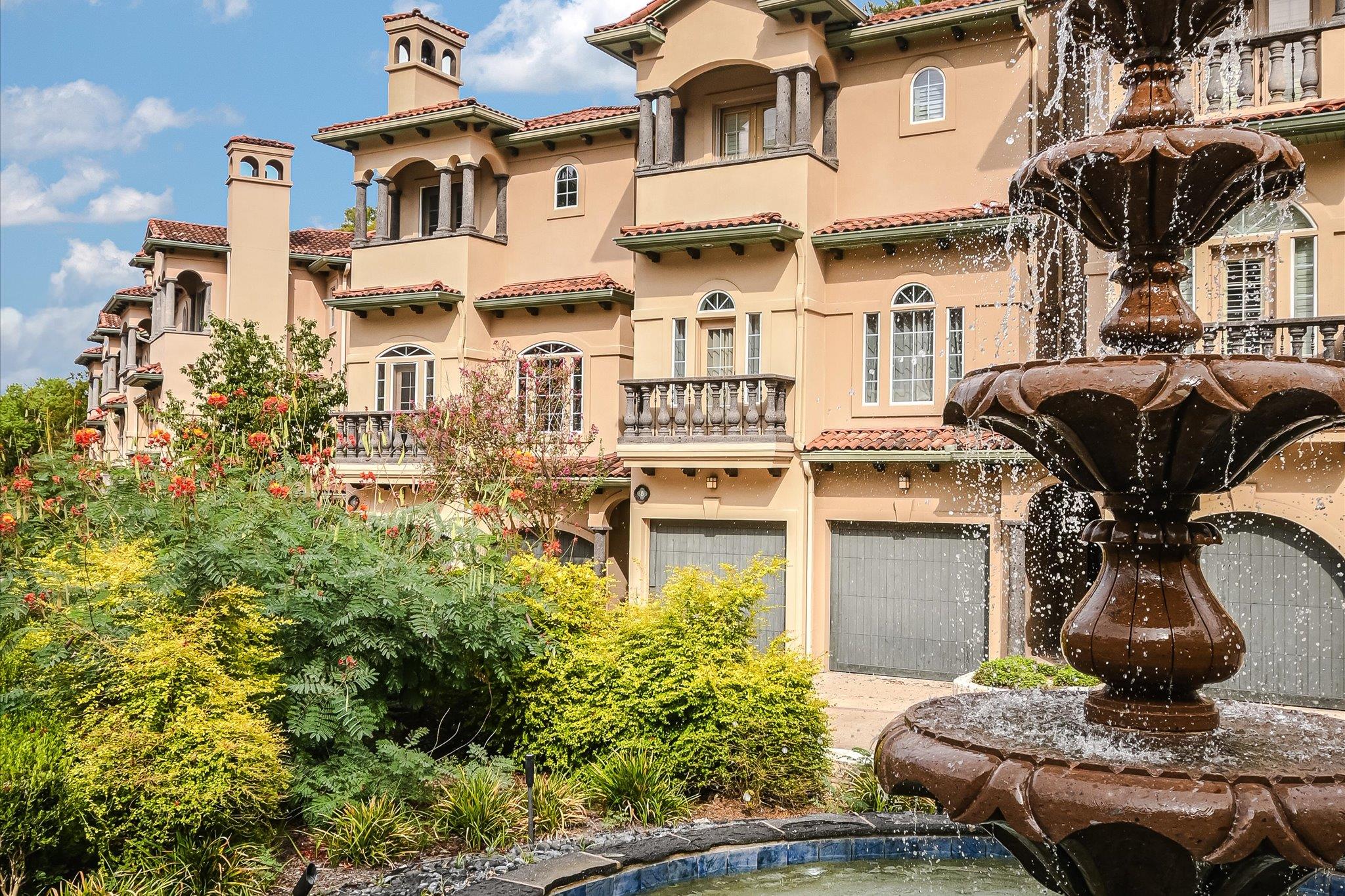Mediterranean-style condominium exterior with a tiered fountain and landscaped gardens.