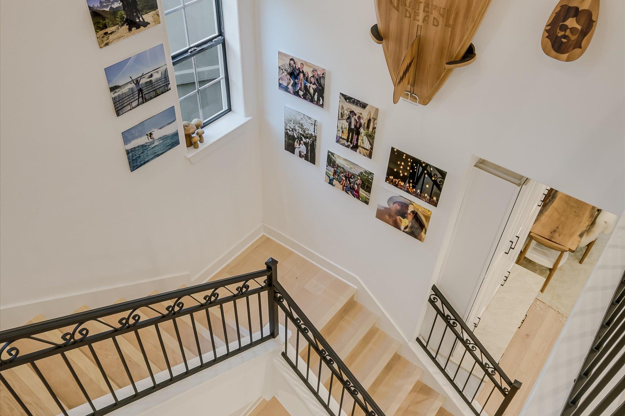Light wood staircase with black iron railings, family photos on the walls, and a canoe mounted overhead.