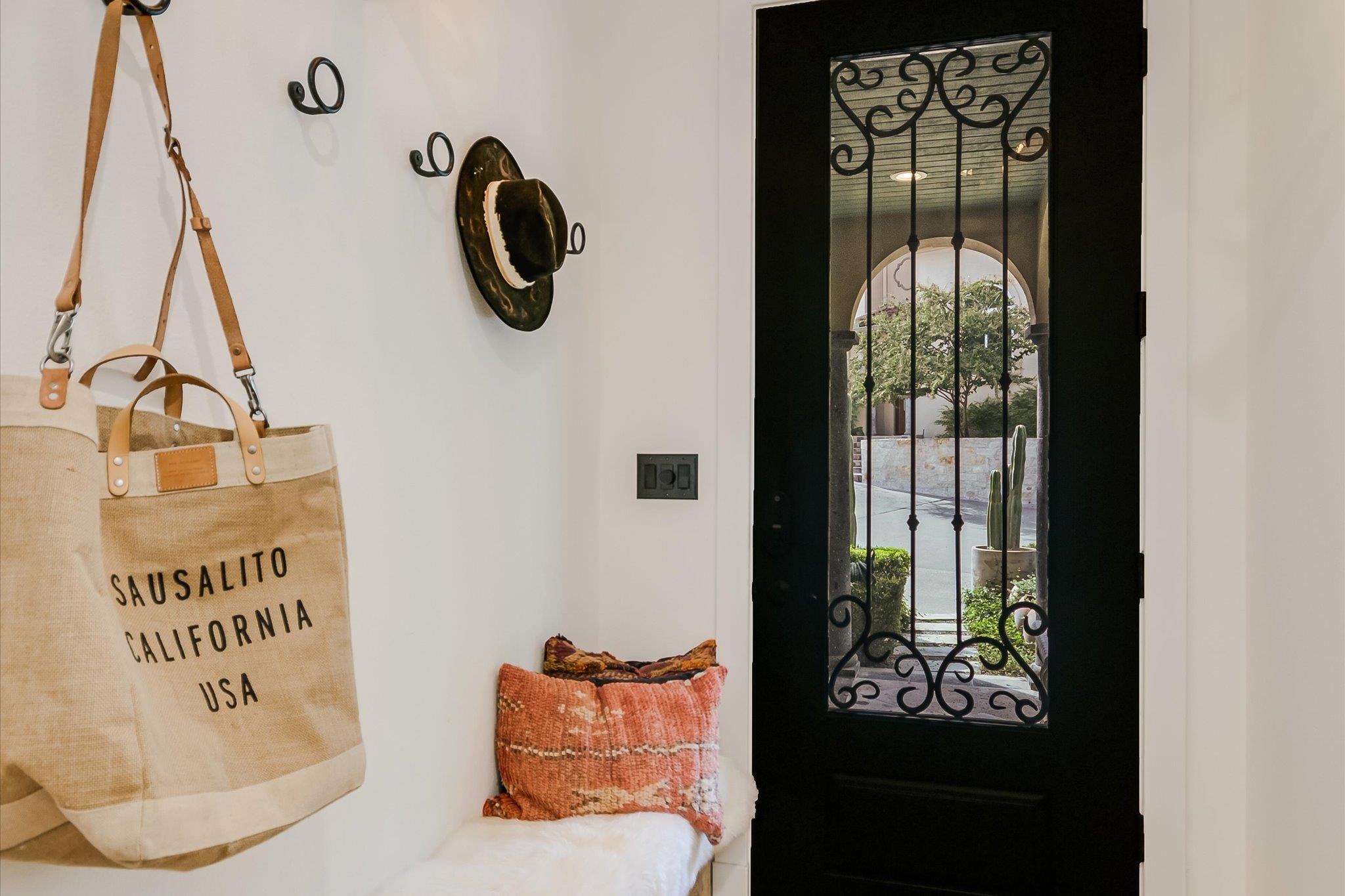 Entryway with an ornate black glass front door, built-in bench, and hanging canvas tote.