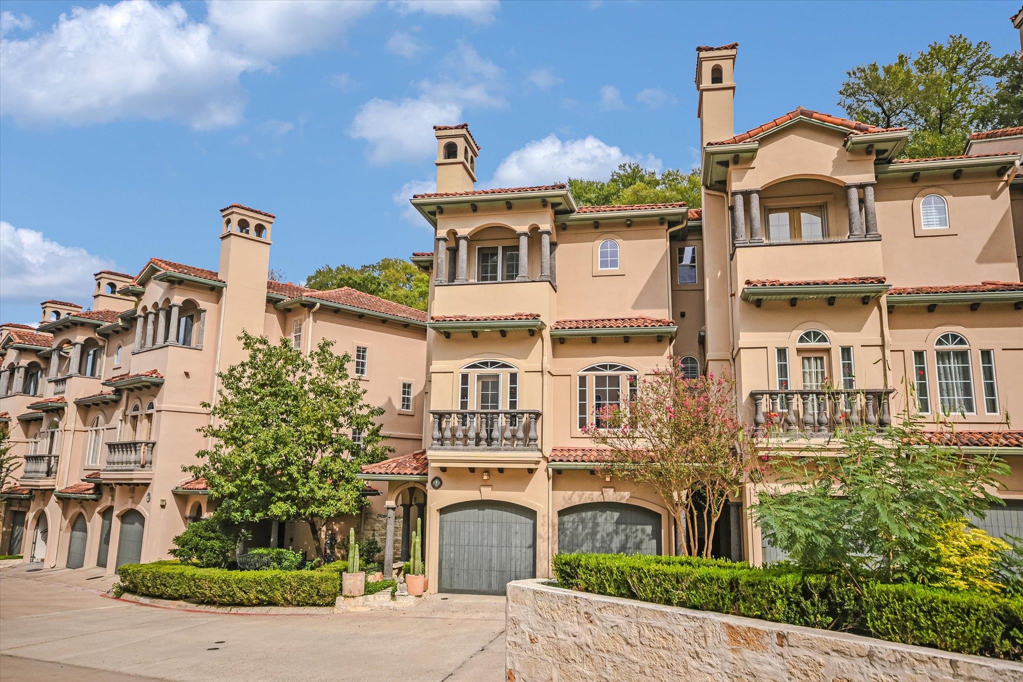 Mediterranean-style townhomes with red tile roofs, arched balconies, and ground-level garages.