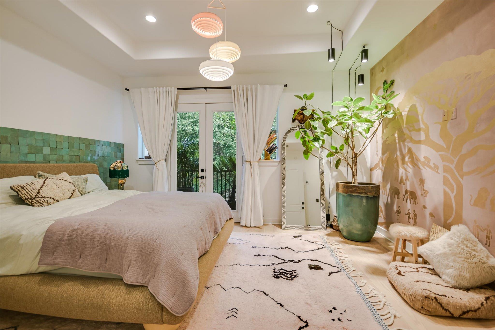 Furnished bedroom with a green tile accent wall, glass door, pendant lights, and a large potted plant.