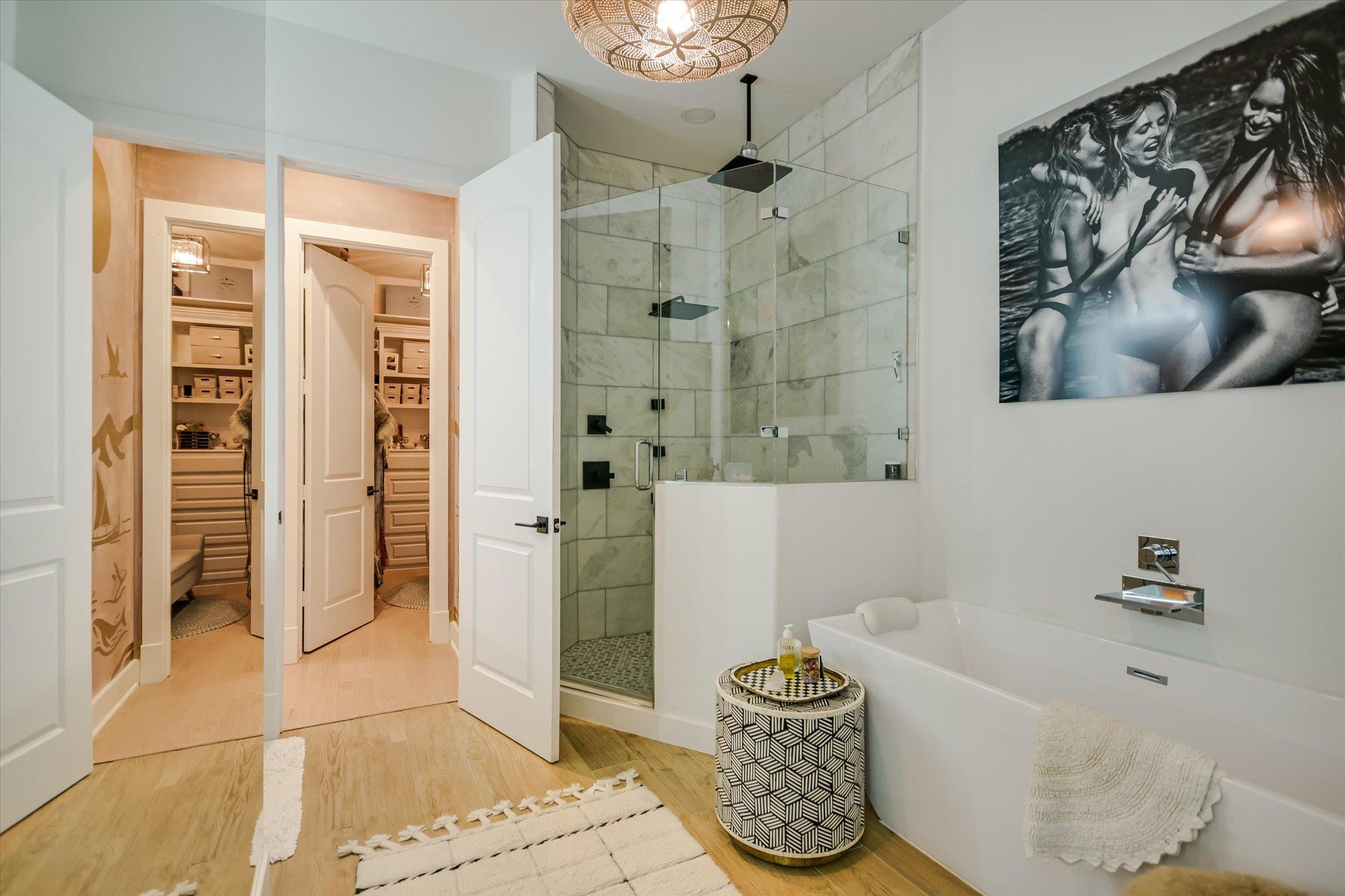 Bathroom with a freestanding tub, marble-tile shower, and two open walk-in closets.