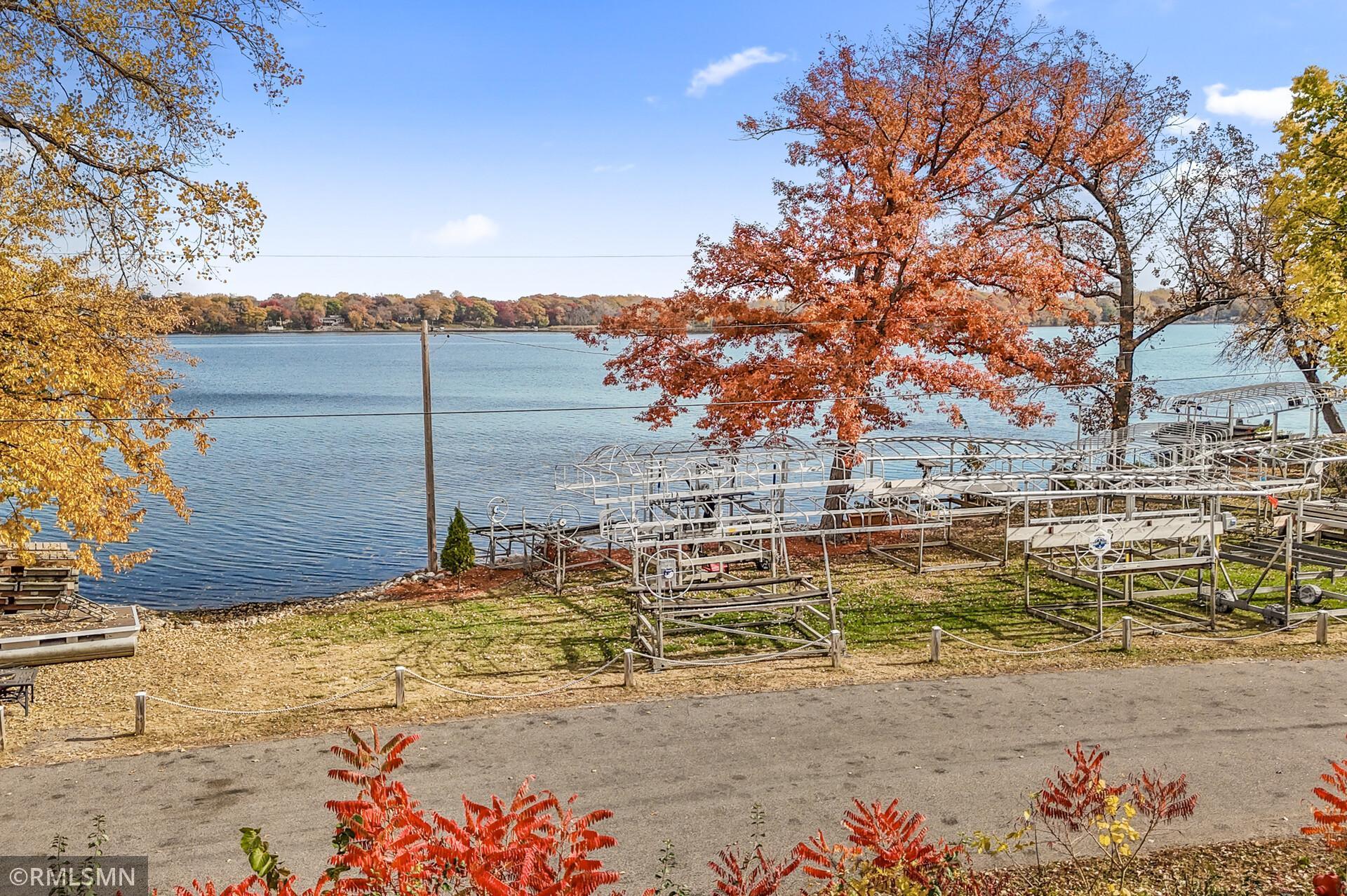 Lakeshore with boat lifts and docks, framed by colorful autumn trees.