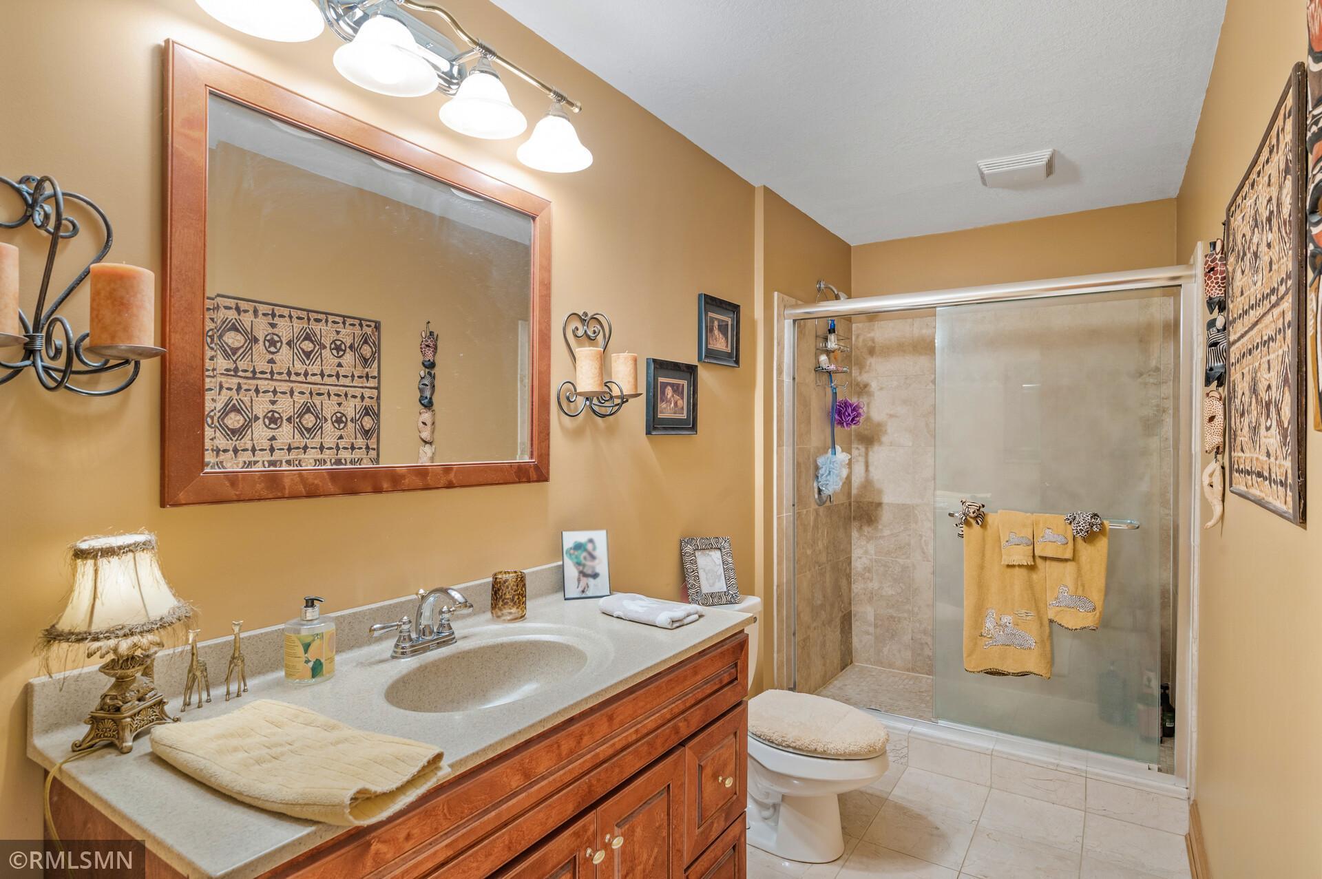 Bathroom with a wood vanity and large mirror beside a tiled glass-enclosed shower.