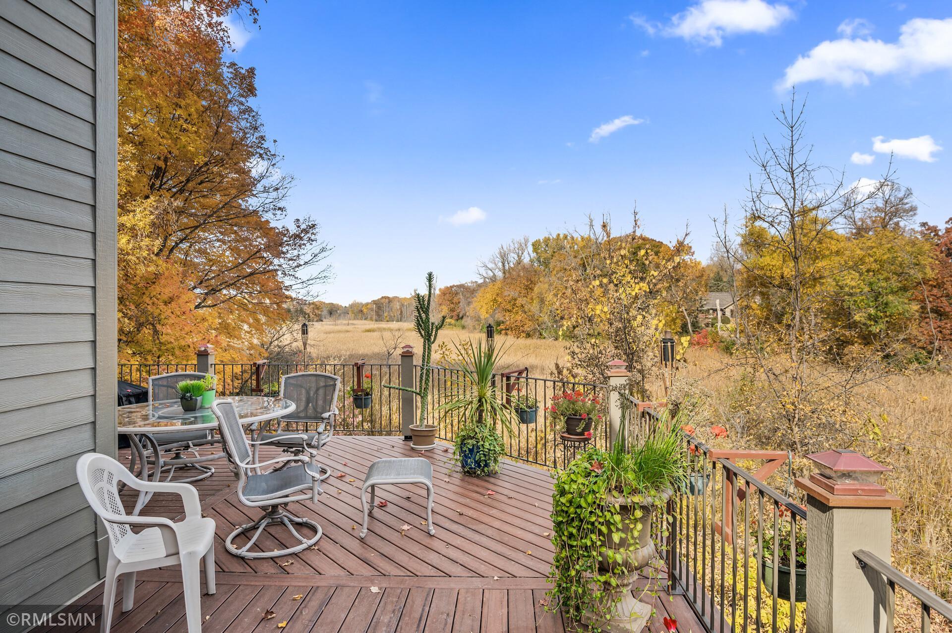 Furnished deck overlooking an open meadow and colorful autumn trees.