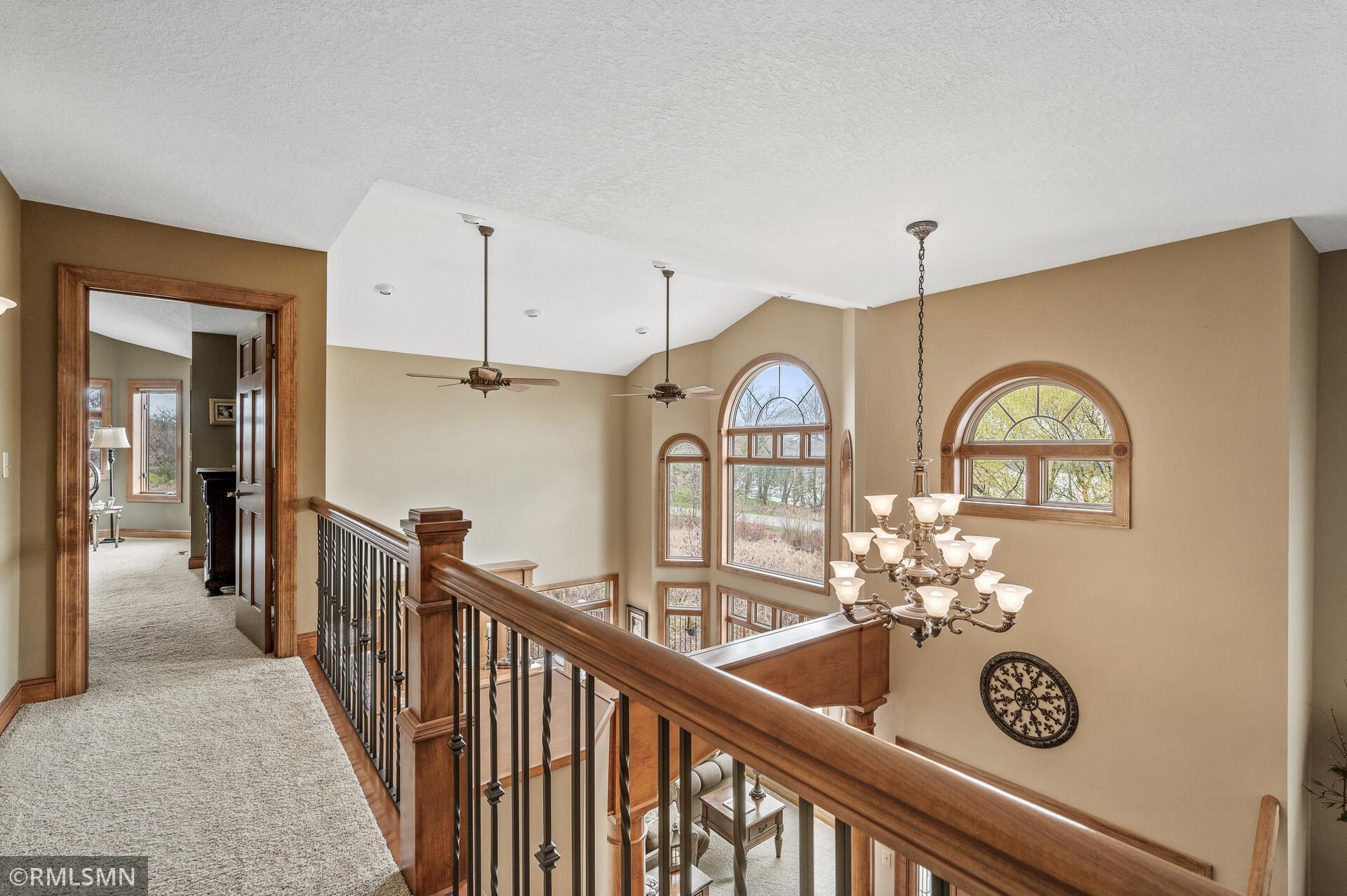 Upstairs landing overlooking a two-story foyer with arched windows and a chandelier.