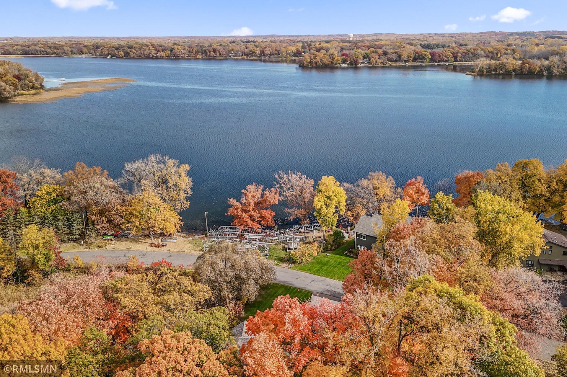 Aerial view of a lake and lakeside homes surrounded by colorful autumn foliage.