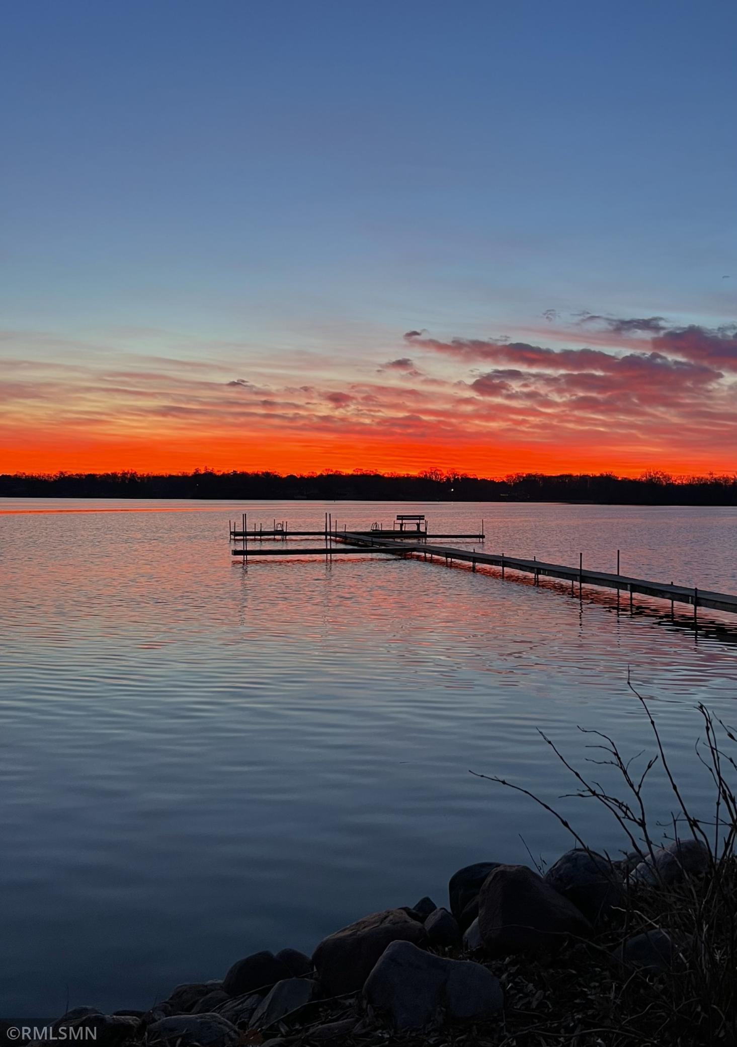 Lake at sunset with a long dock extending across calm water.