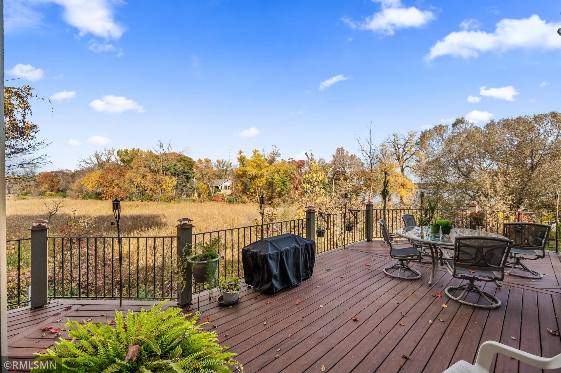 Wooden deck with patio furniture overlooking a golden marsh and autumn trees.