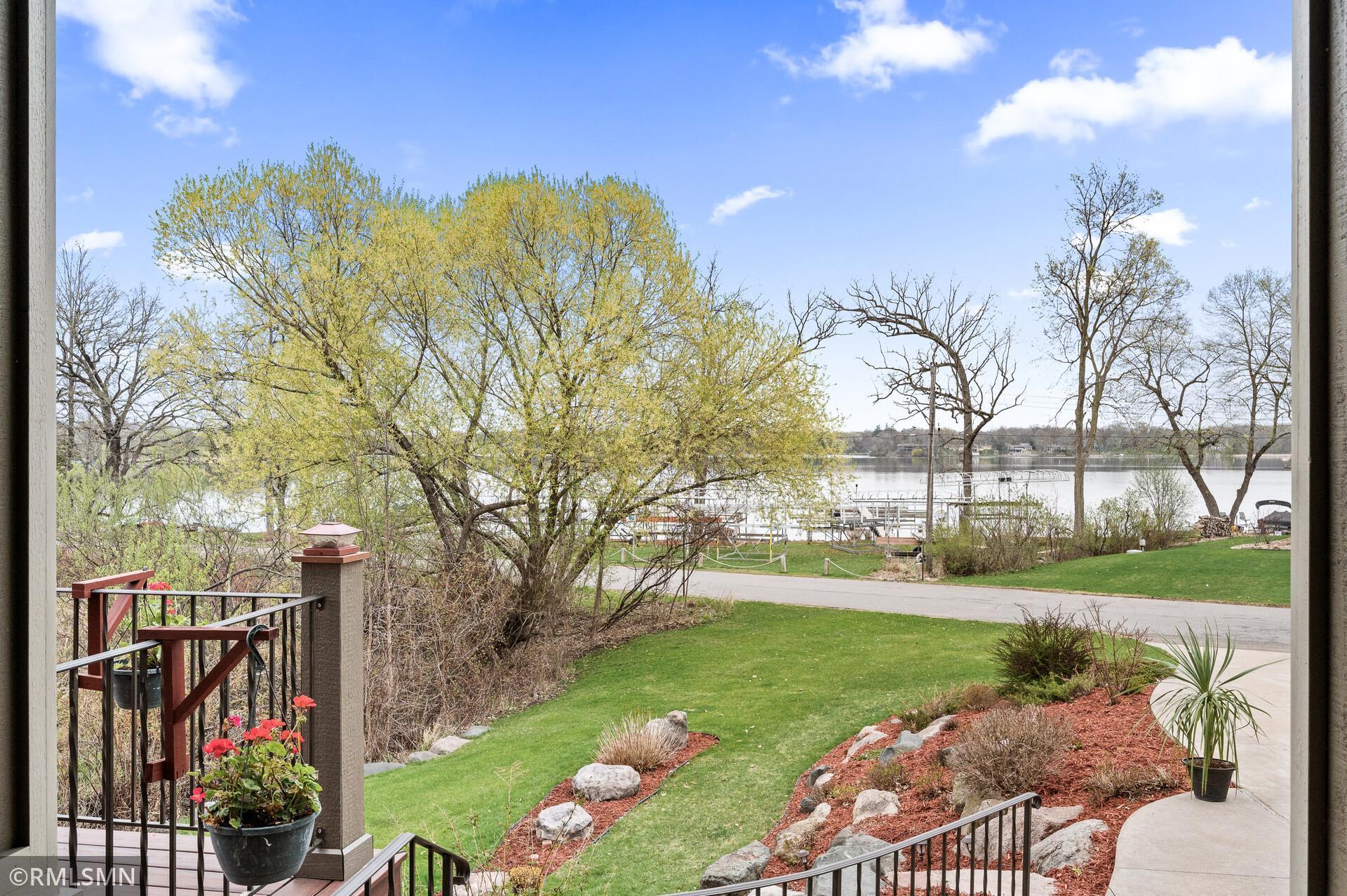 Lake and docks beyond a landscaped lawn, viewed from the home’s deck.