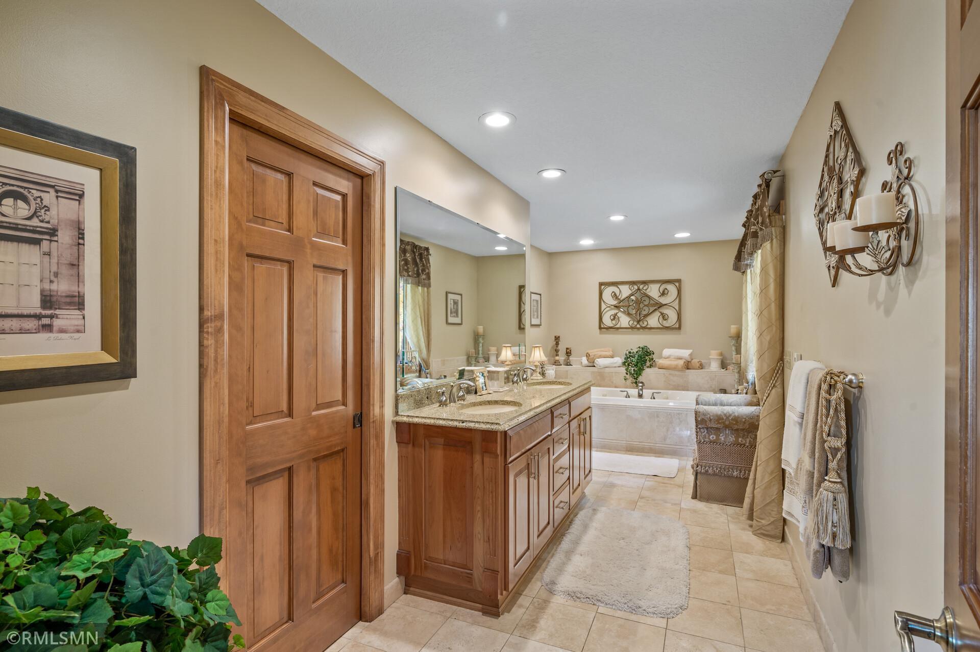 Bathroom with a long wood vanity and a built-in soaking tub.