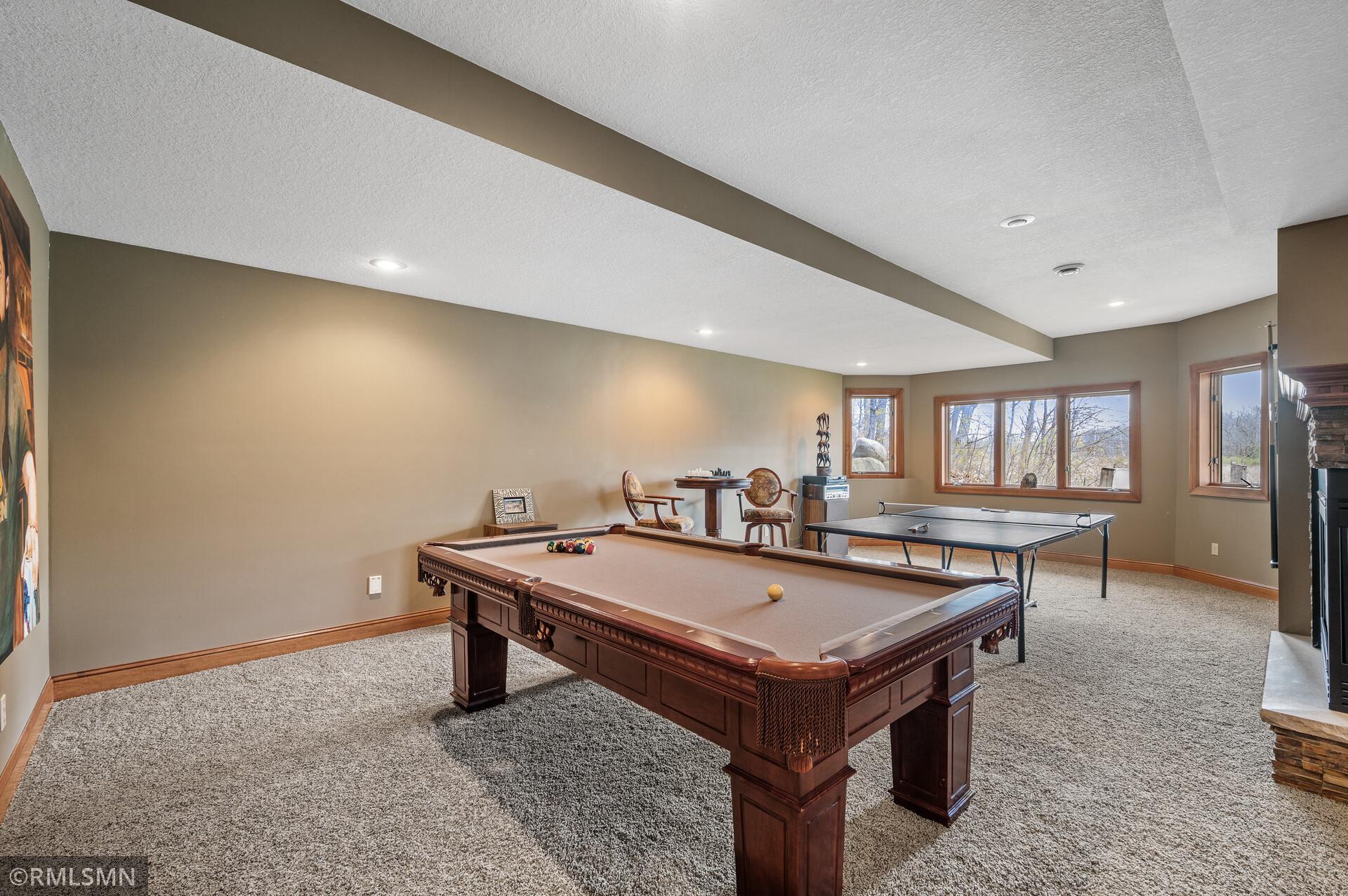 Recreation room with a wooden pool table, ping-pong table, and windows.