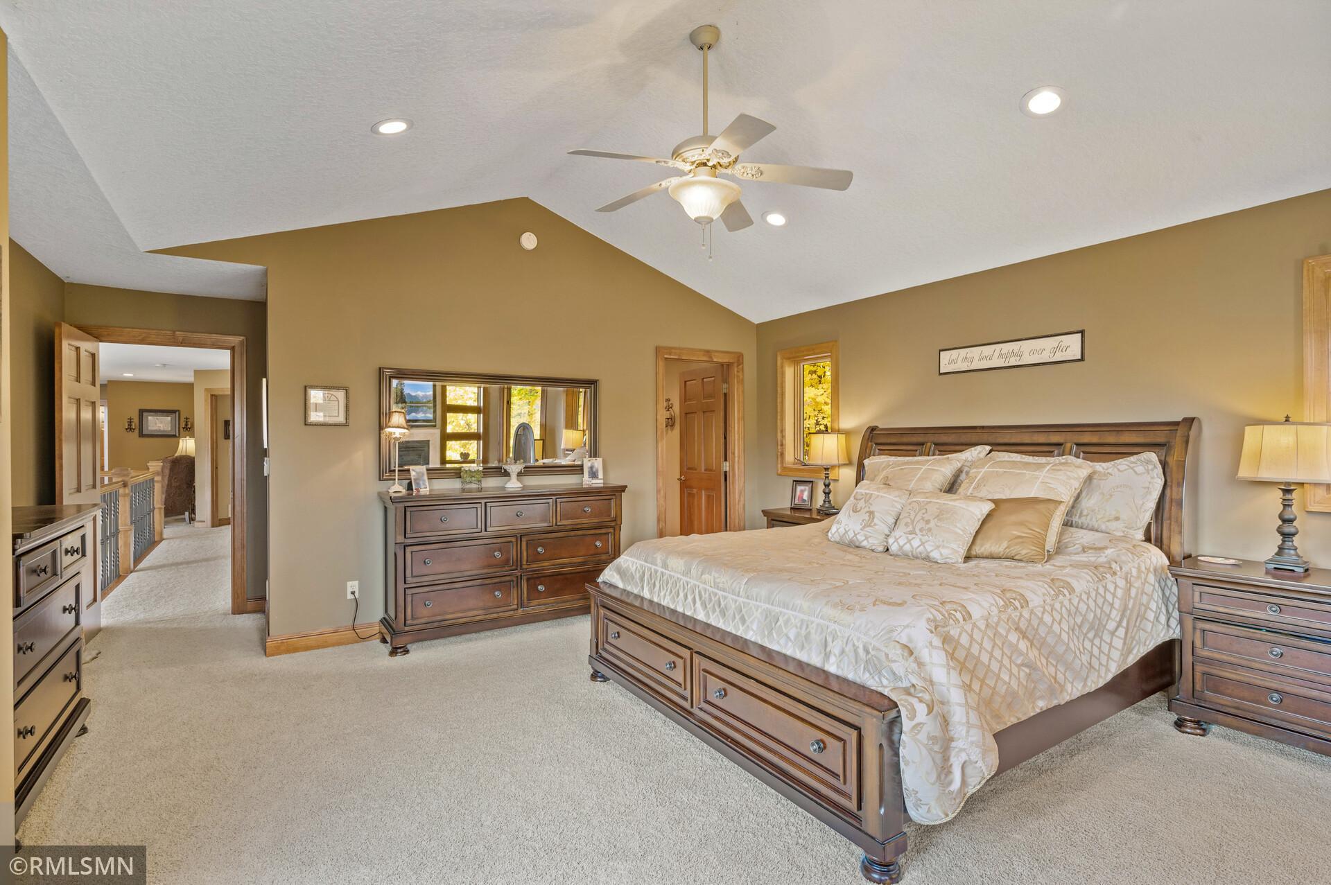 Furnished bedroom with a large wooden bed, matching dressers, and a ceiling fan.