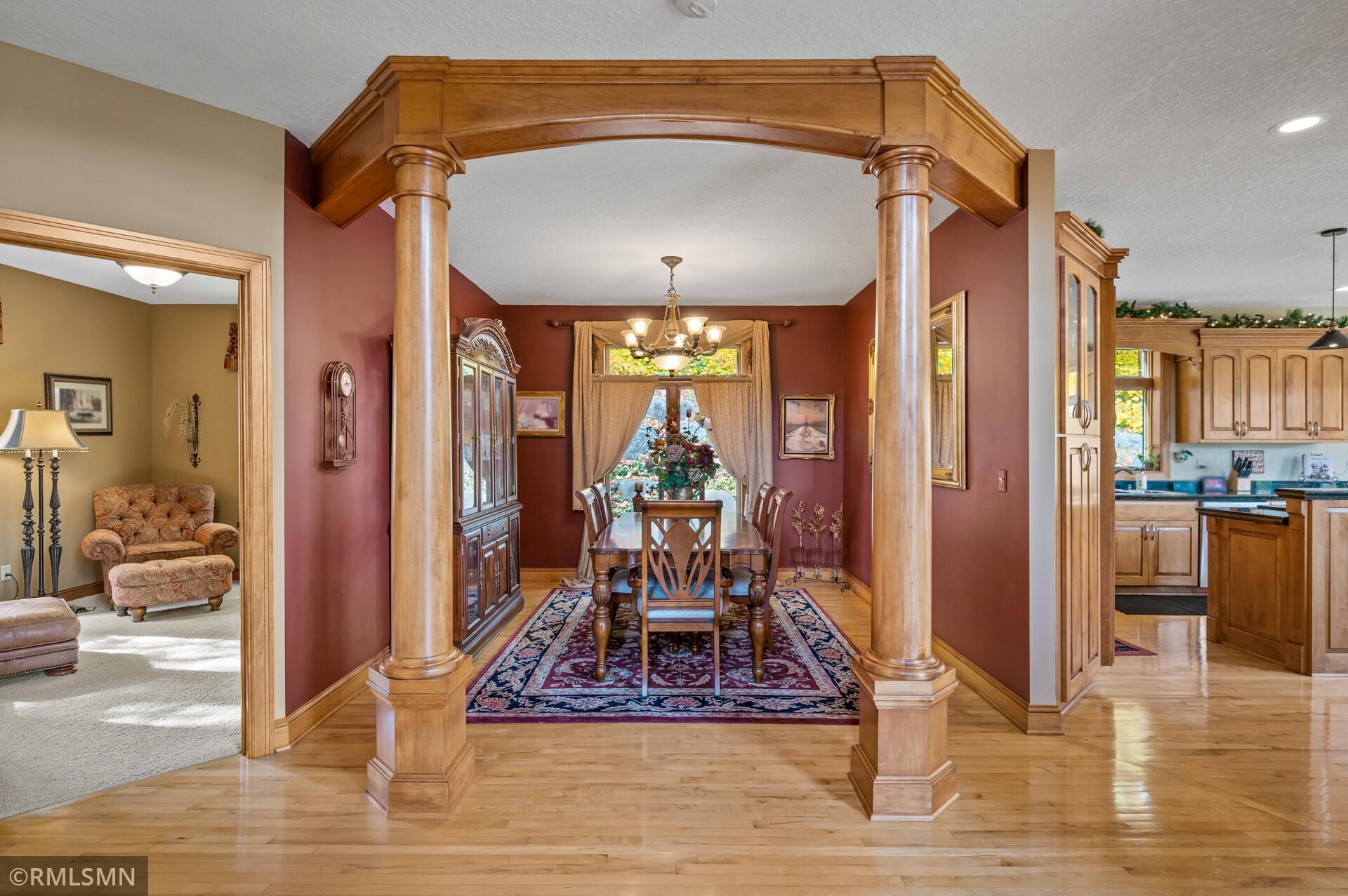Dining room with a carved wooden arch, formal table, and patterned rug.