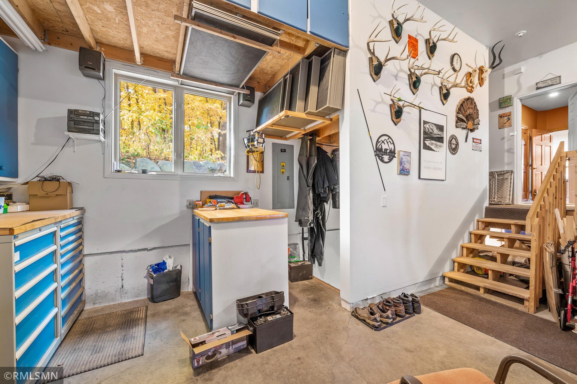 Garage workshop with blue tool drawers, mounted antlers, a workbench, and wooden stairs.