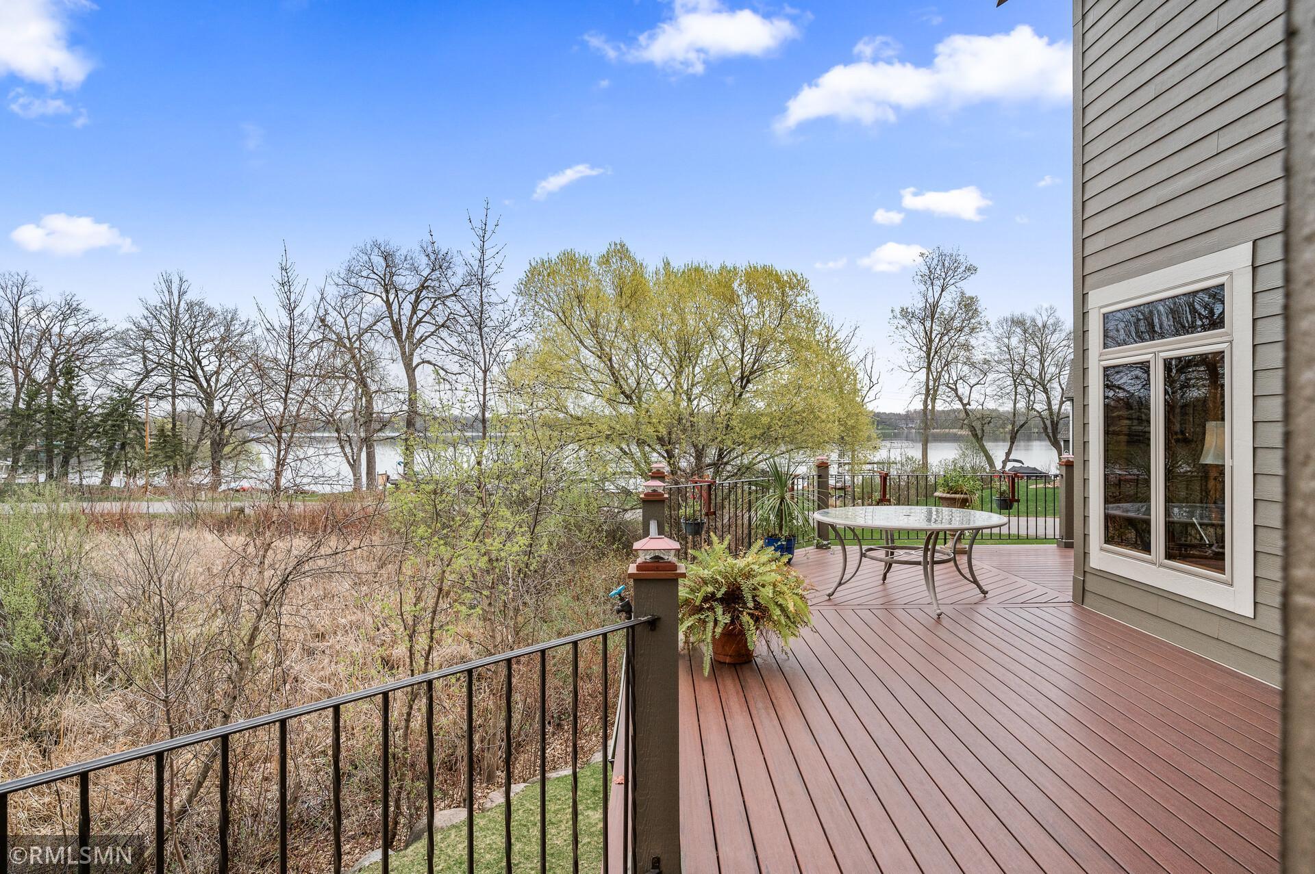 Raised deck with patio table overlooks a lake through budding trees.