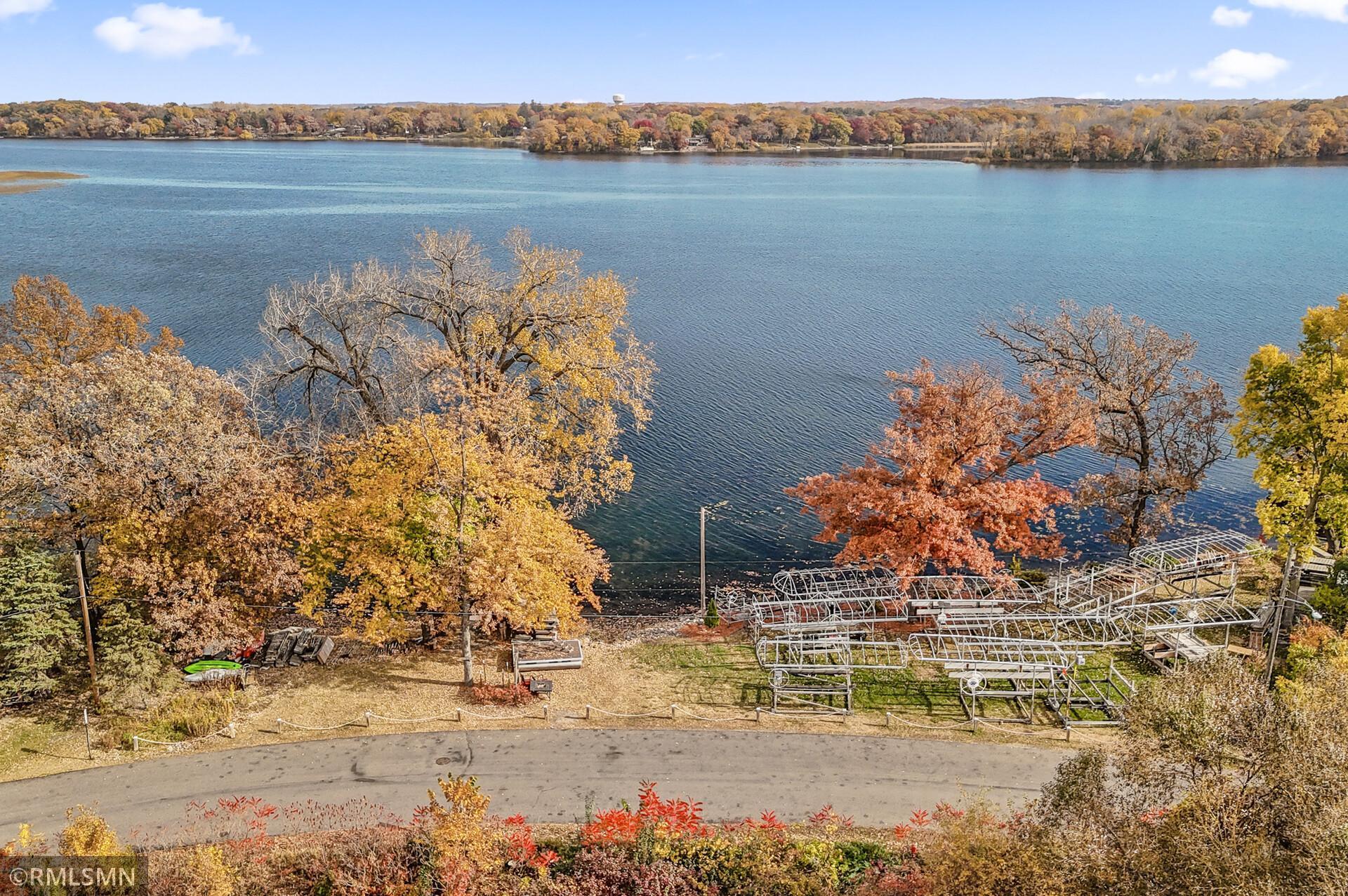 Aerial view of a lake framed by autumn trees, with boat lifts along the shore.