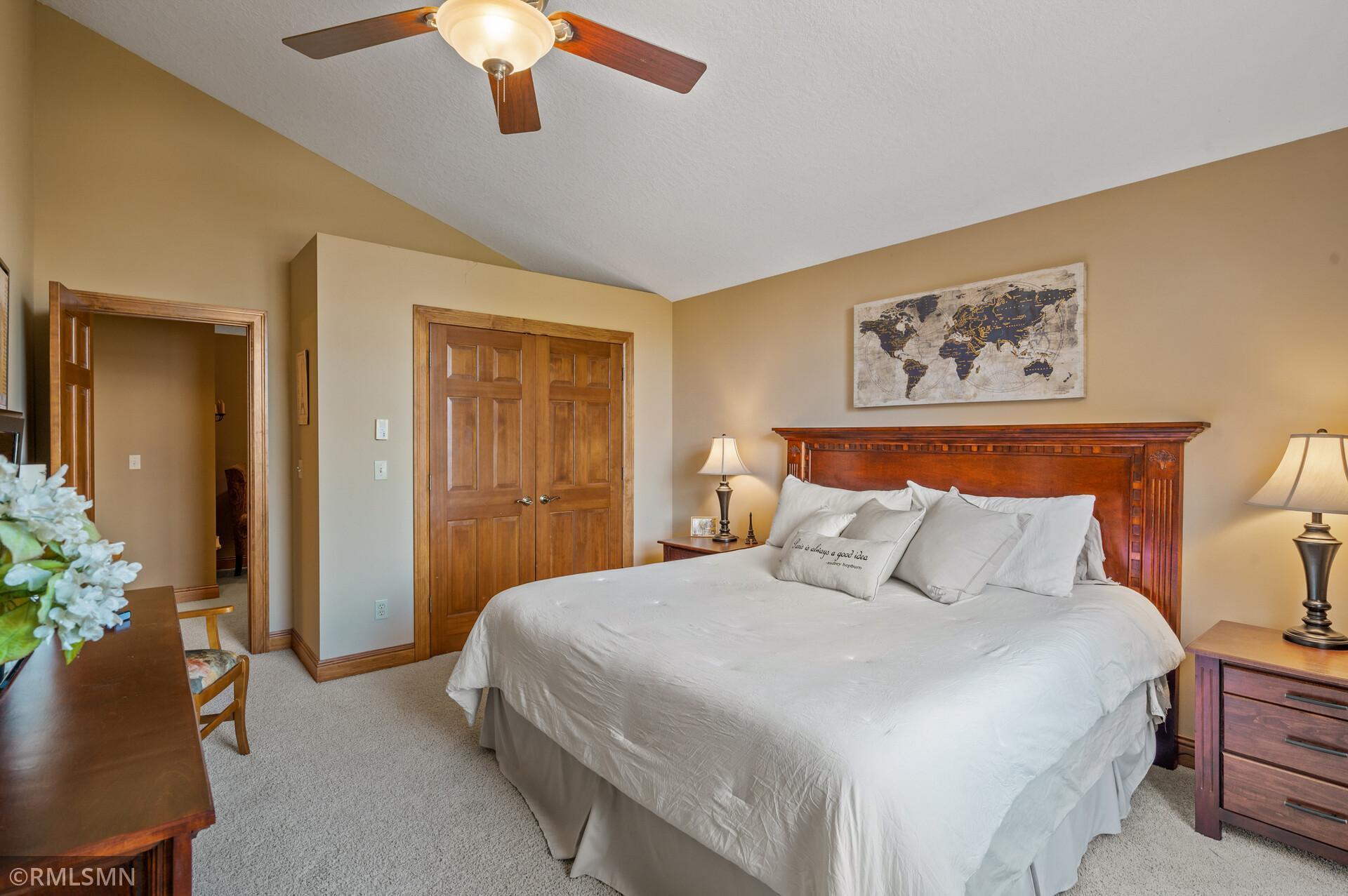 Furnished bedroom with a large white bed, carved wooden headboard, and world map wall art.