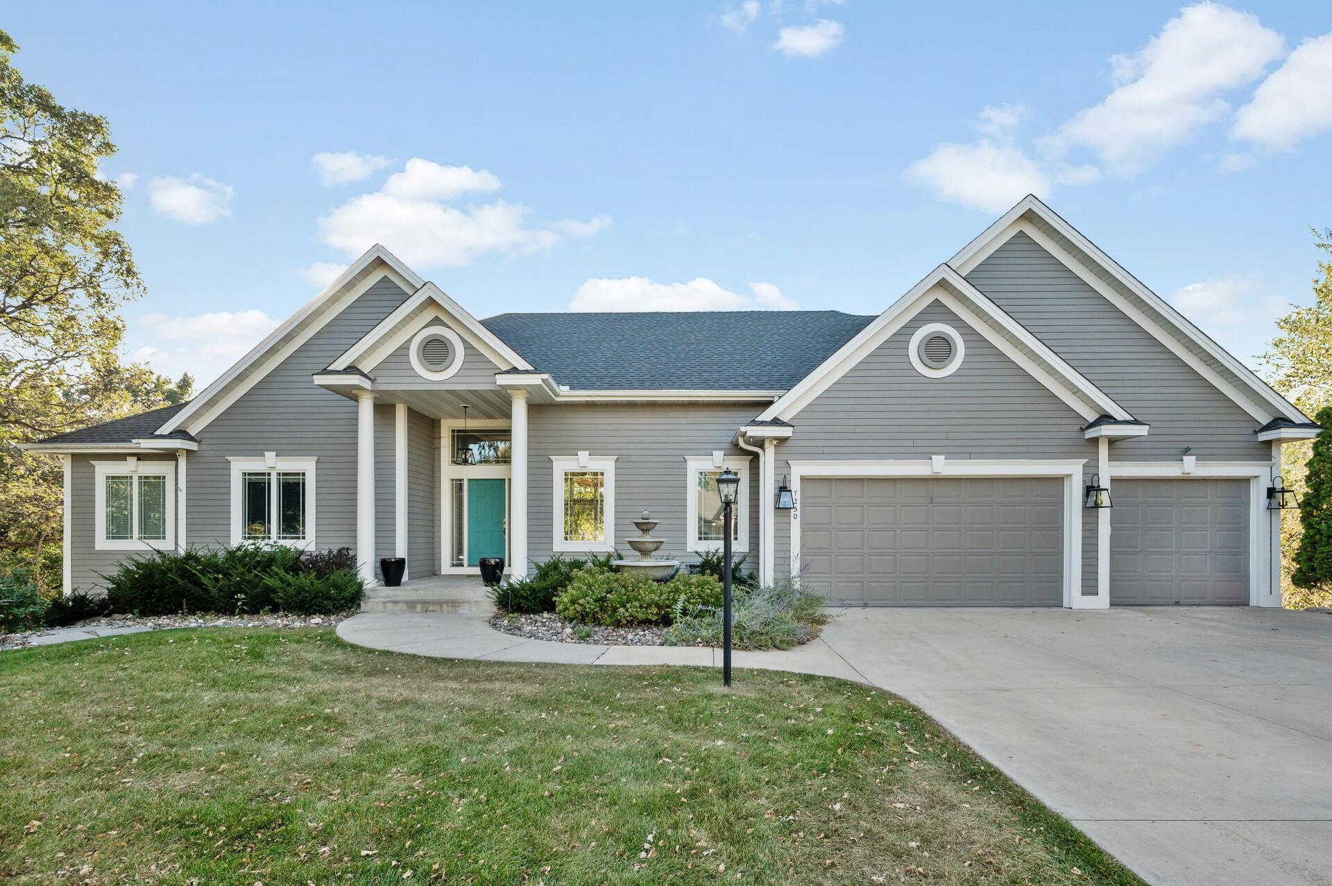 Gray home with a turquoise front door, prominent gables, and a three-car garage.