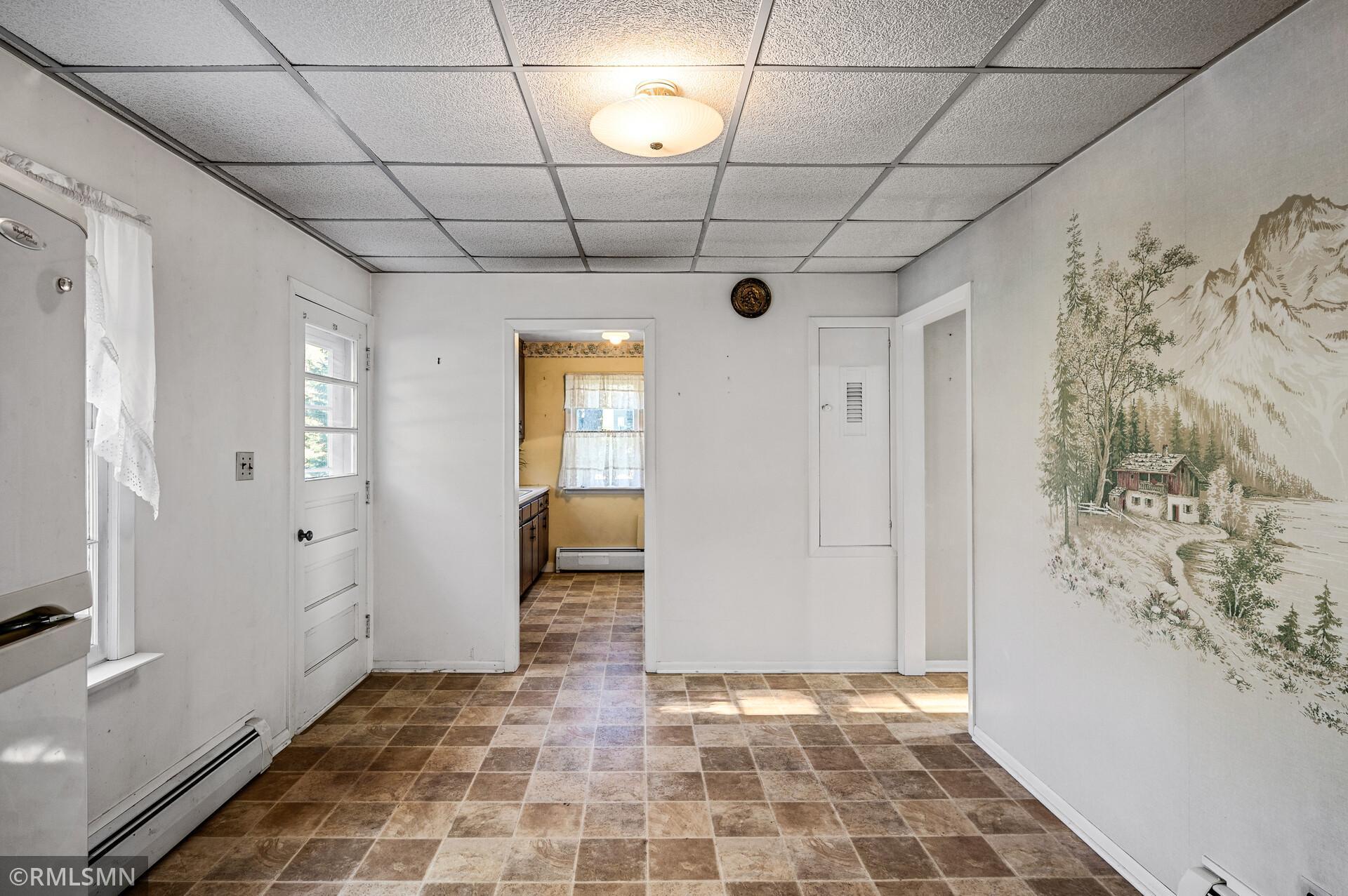 Vacant kitchen area with brown tile flooring and a mountain-and-cabin mural.