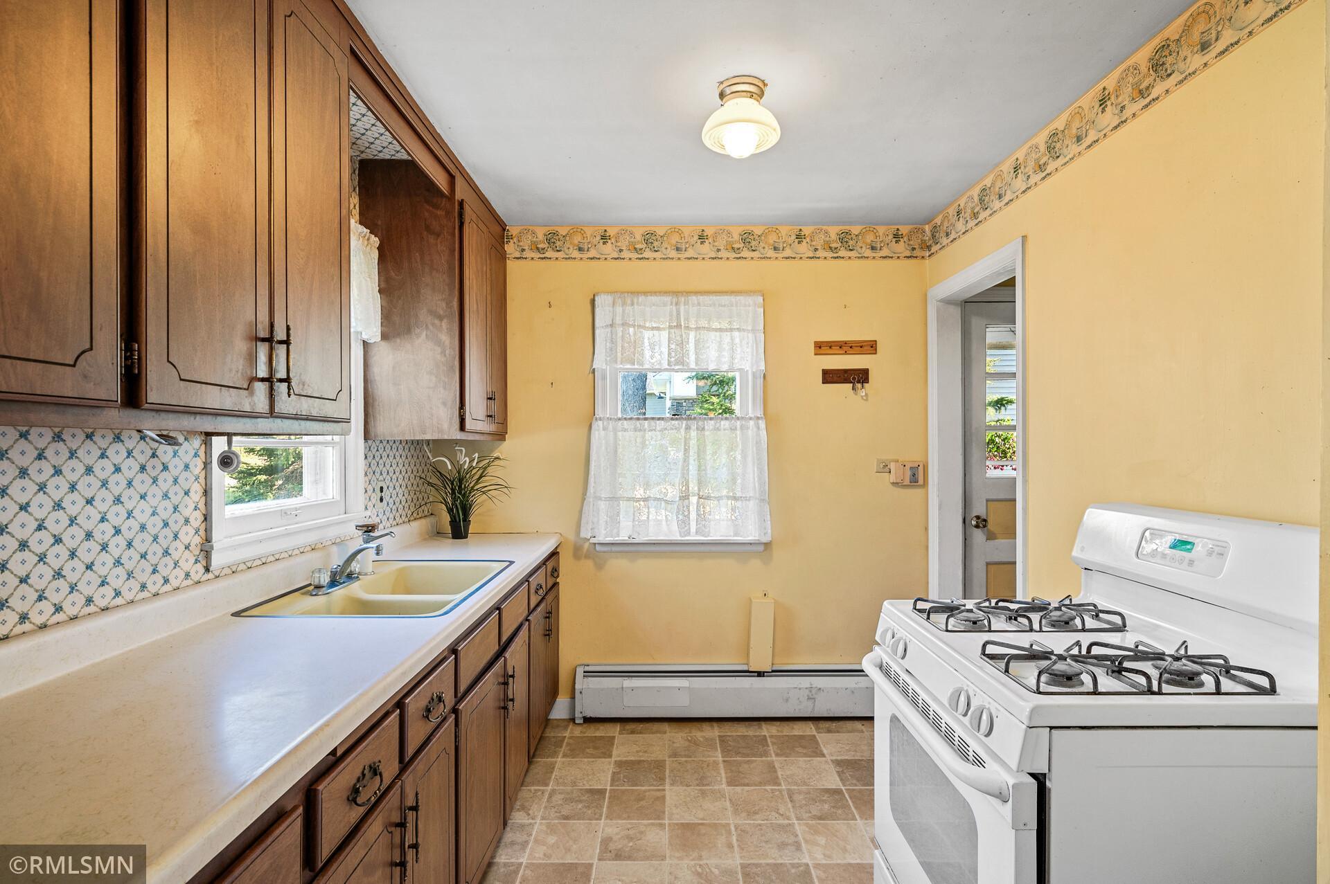 Kitchen with dark wood cabinets, patterned backsplash, yellow walls, and a white gas range.
