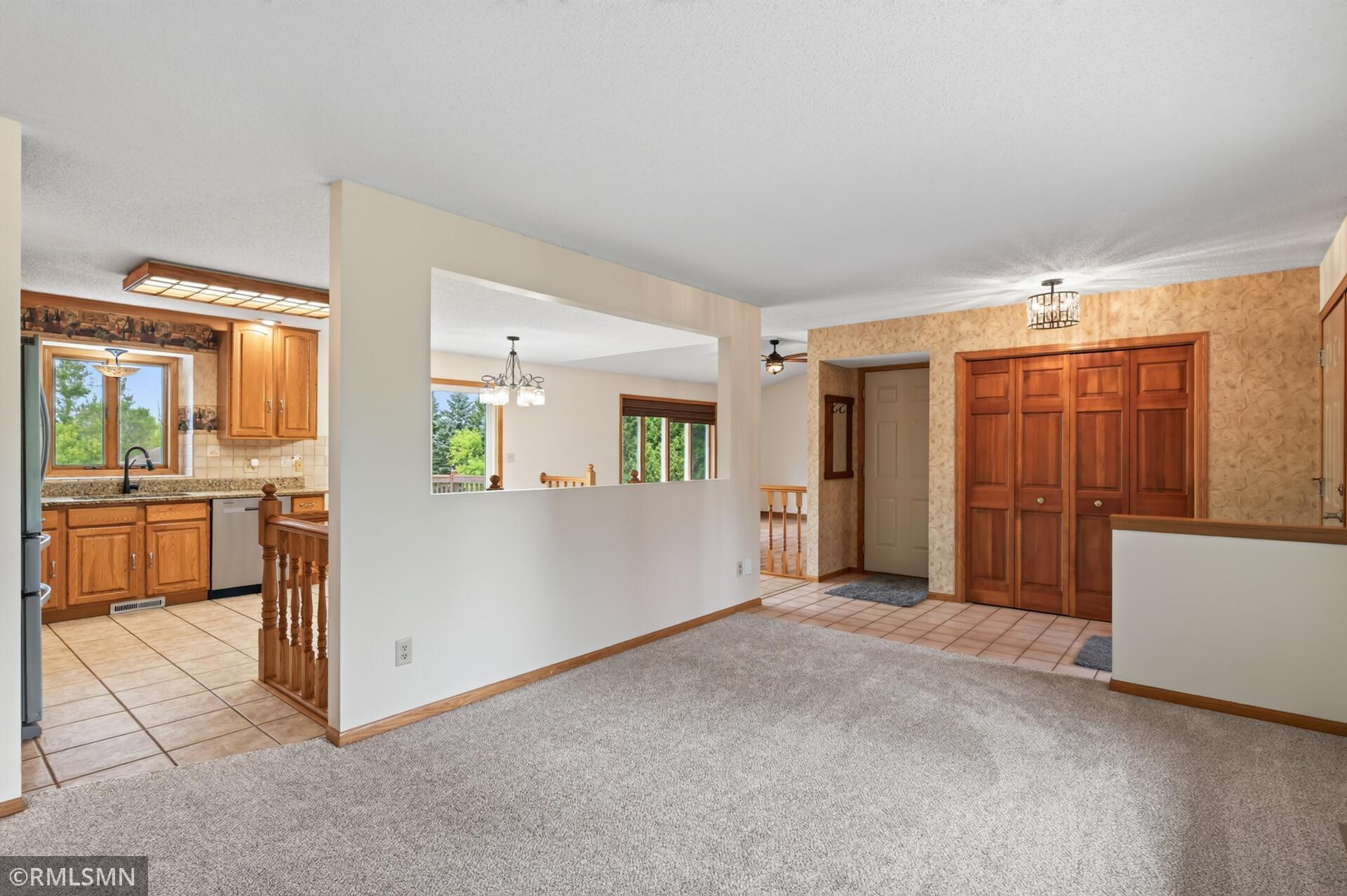 Carpeted living area beside a tiled entry and oak-cabinet kitchen.
