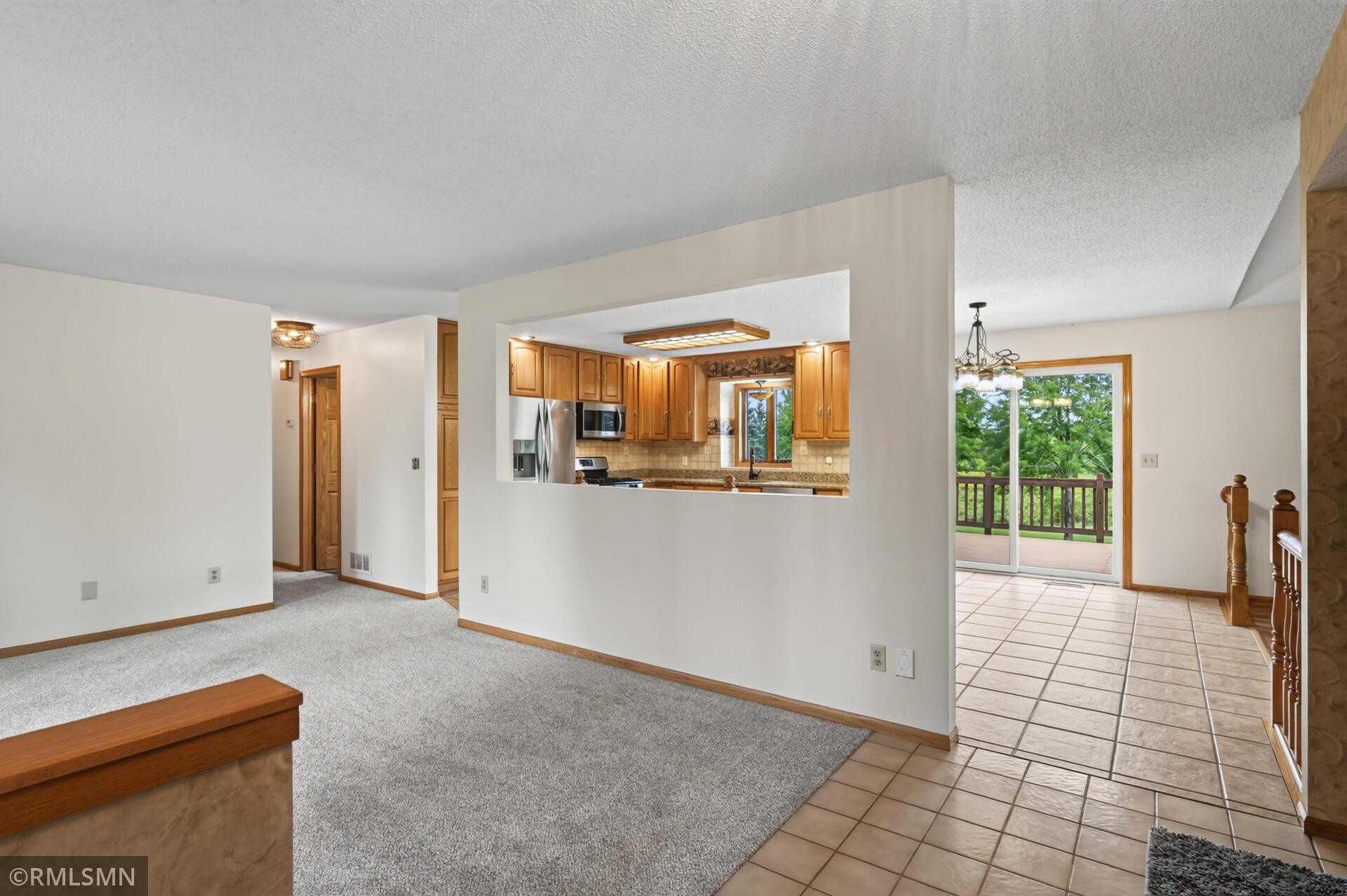 Living room with kitchen pass-through and tiled dining area opening onto a deck.