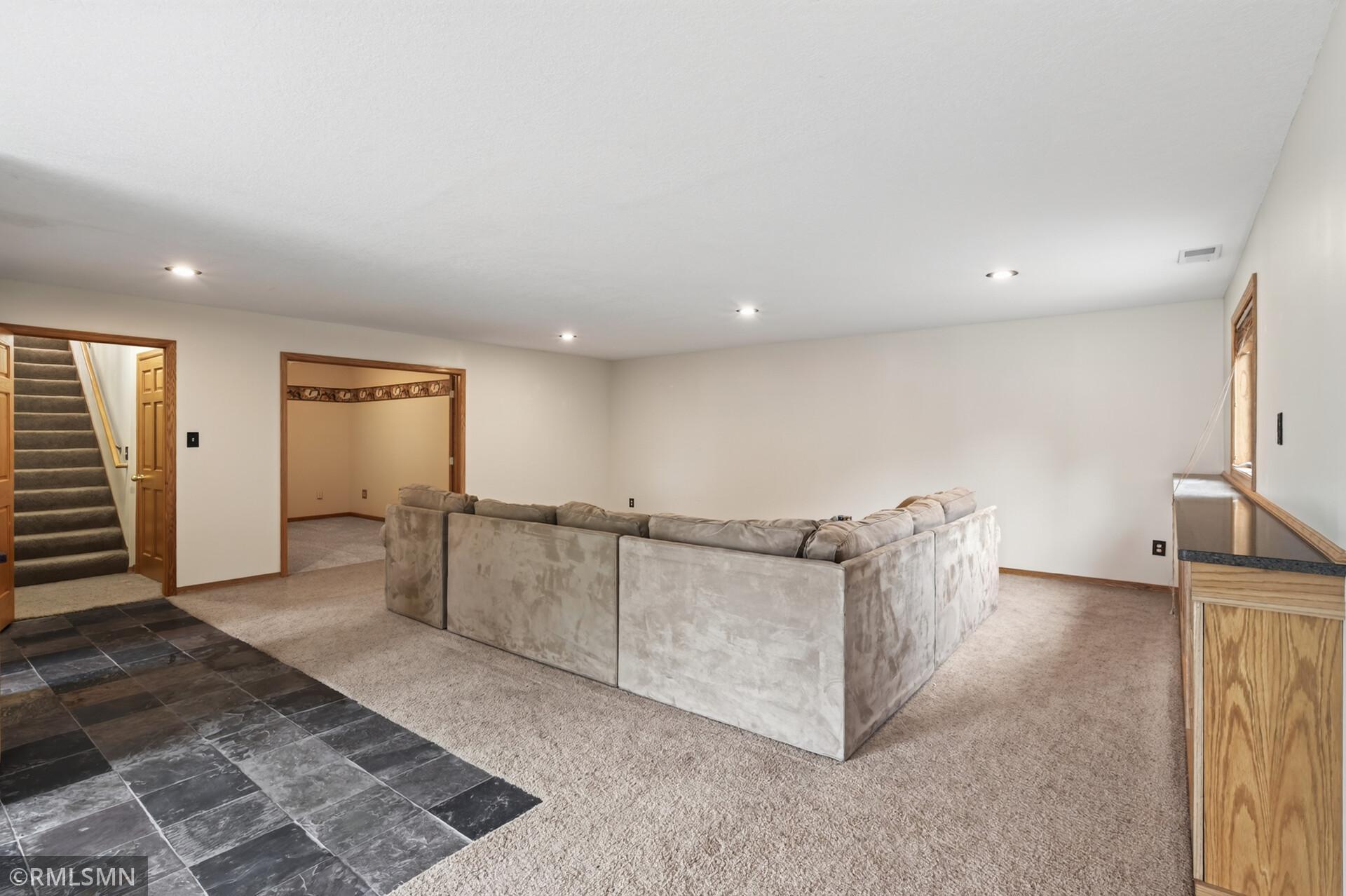 Spacious family room with a large sectional sofa, staircase, and dark slate tile flooring.