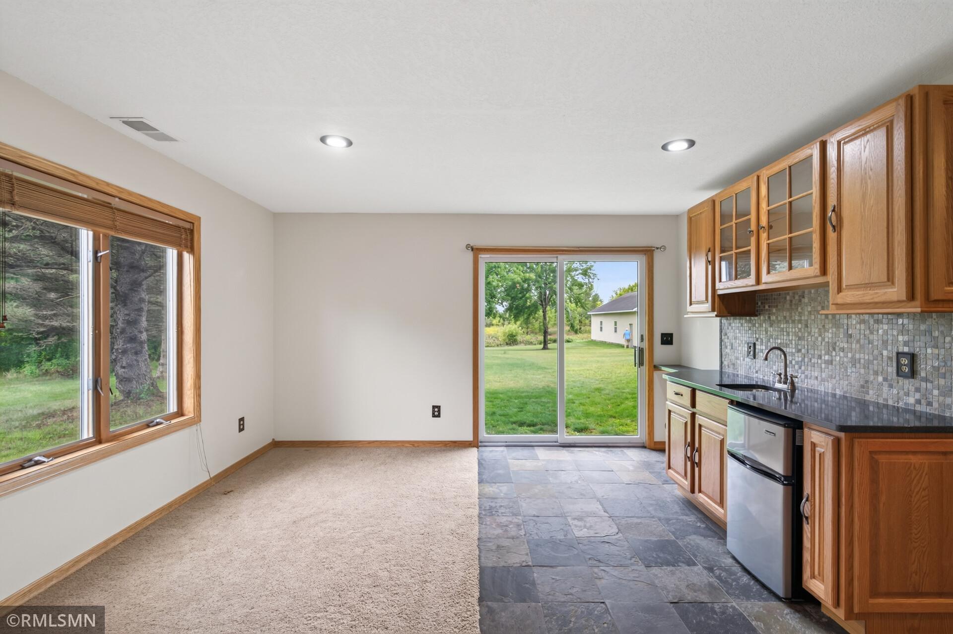 Kitchen and dining area with oak cabinets, gray tile flooring, and a sliding door to the lawn.
