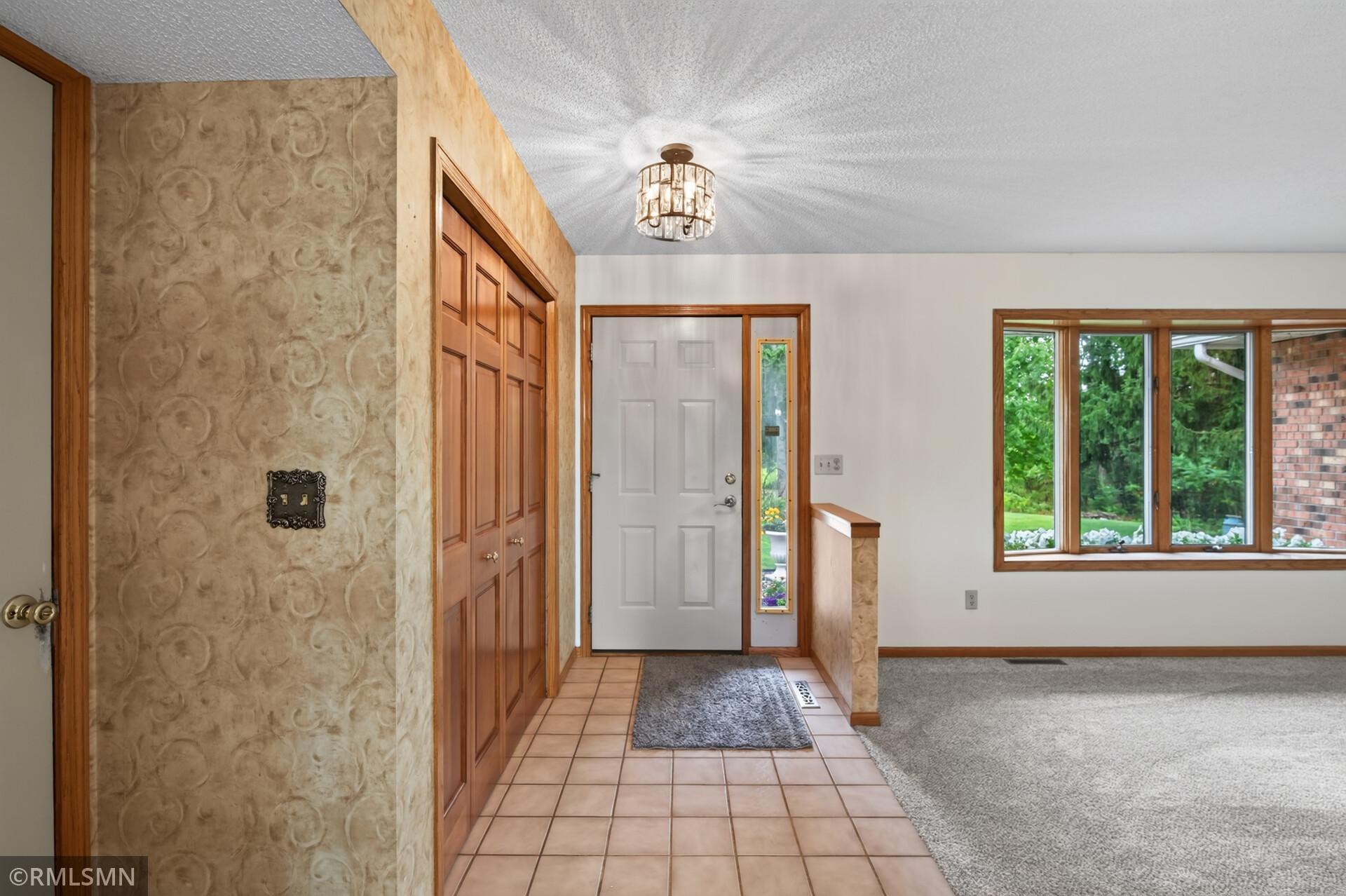 Entry foyer with tiled floor, wood-trimmed closet doors, and a large window beside the front door.