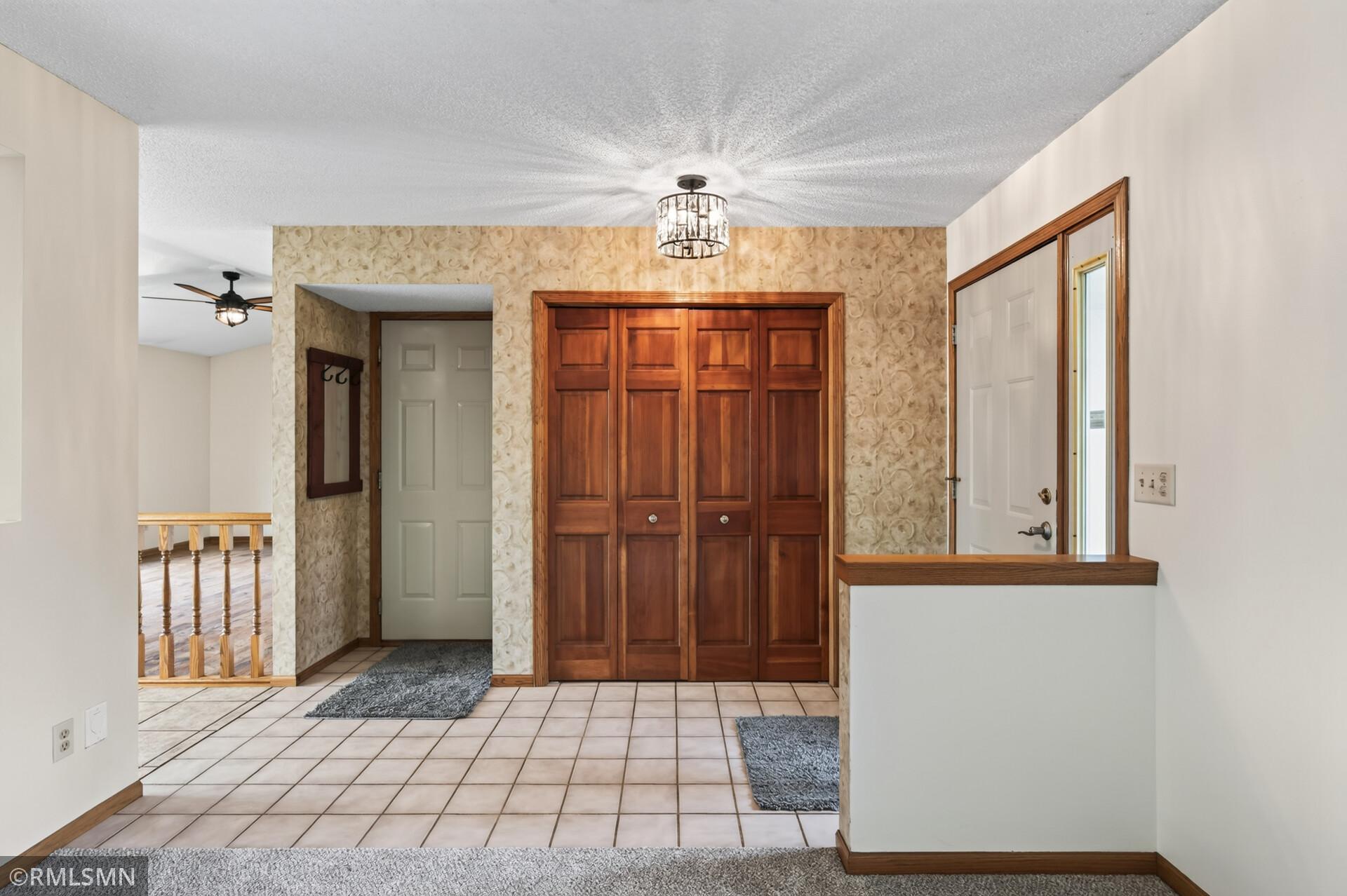 Entry foyer with tiled flooring, a wood-paneled closet, and a white front door.